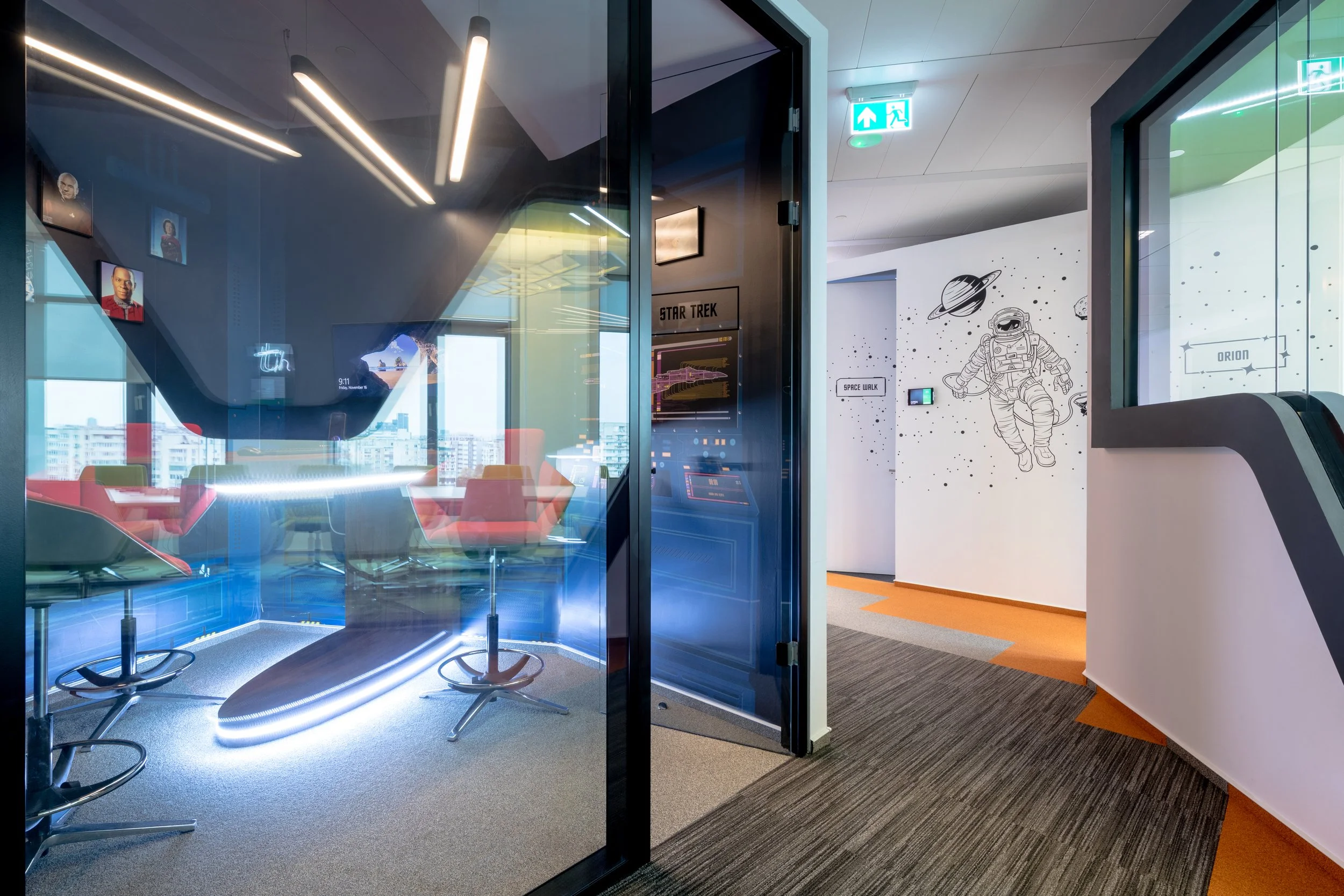 Office meeting room with large glass walls, modern chairs, and a star trek-themed wall with space-themed decorations.