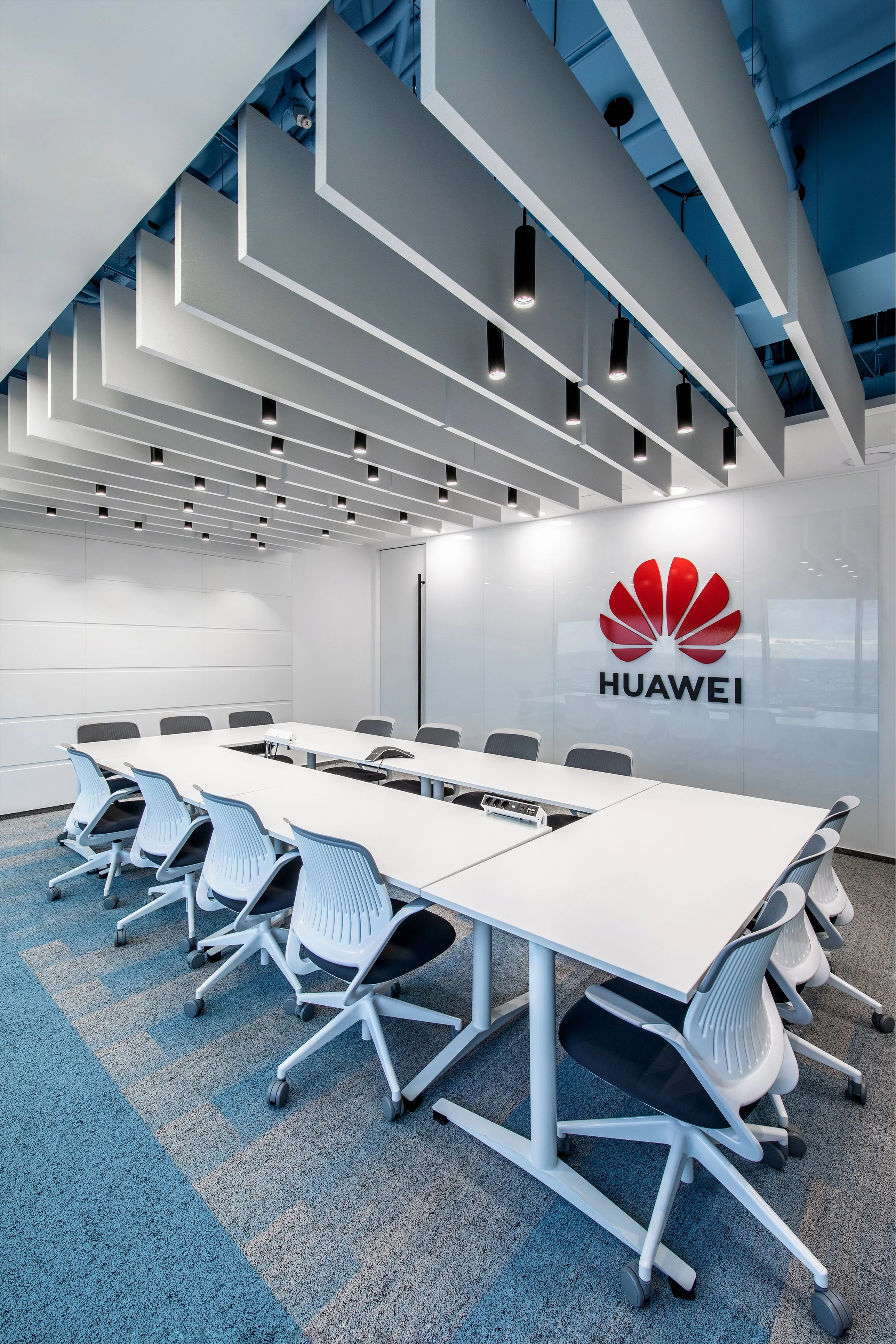 Conference room with a white table, gray chairs, and a Huawei logo on the wall.