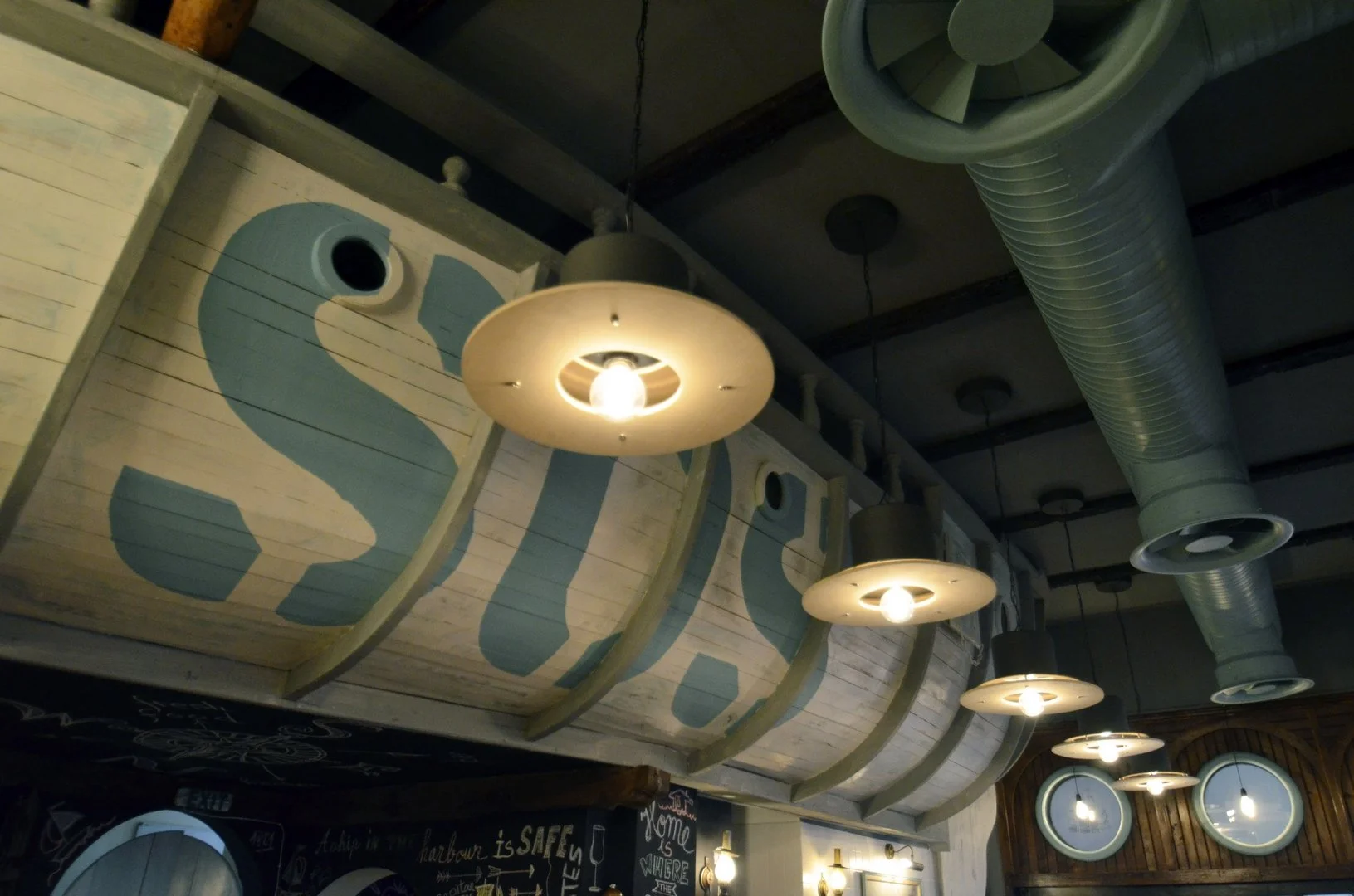 Interior of a restaurant with old boat mounted upside down on the ceiling and hanging pendant lights.
