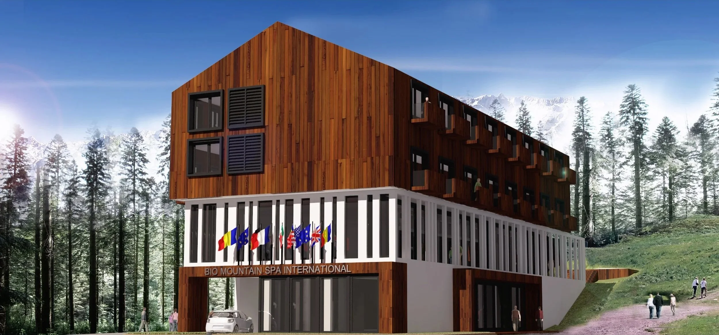 A modern multi-story building with a wooden upper section and a white lower section, featuring flags and the sign 'Bio Mountain Spa International,' set in a forested mountain landscape with a few people walking nearby.