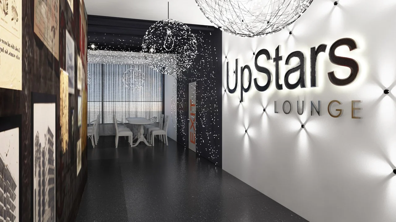 Interior of the Upstars Lounge with illuminated sign, decorative spherical light fixtures, a black partition with exit sign, and a dining area with a white table and chairs.