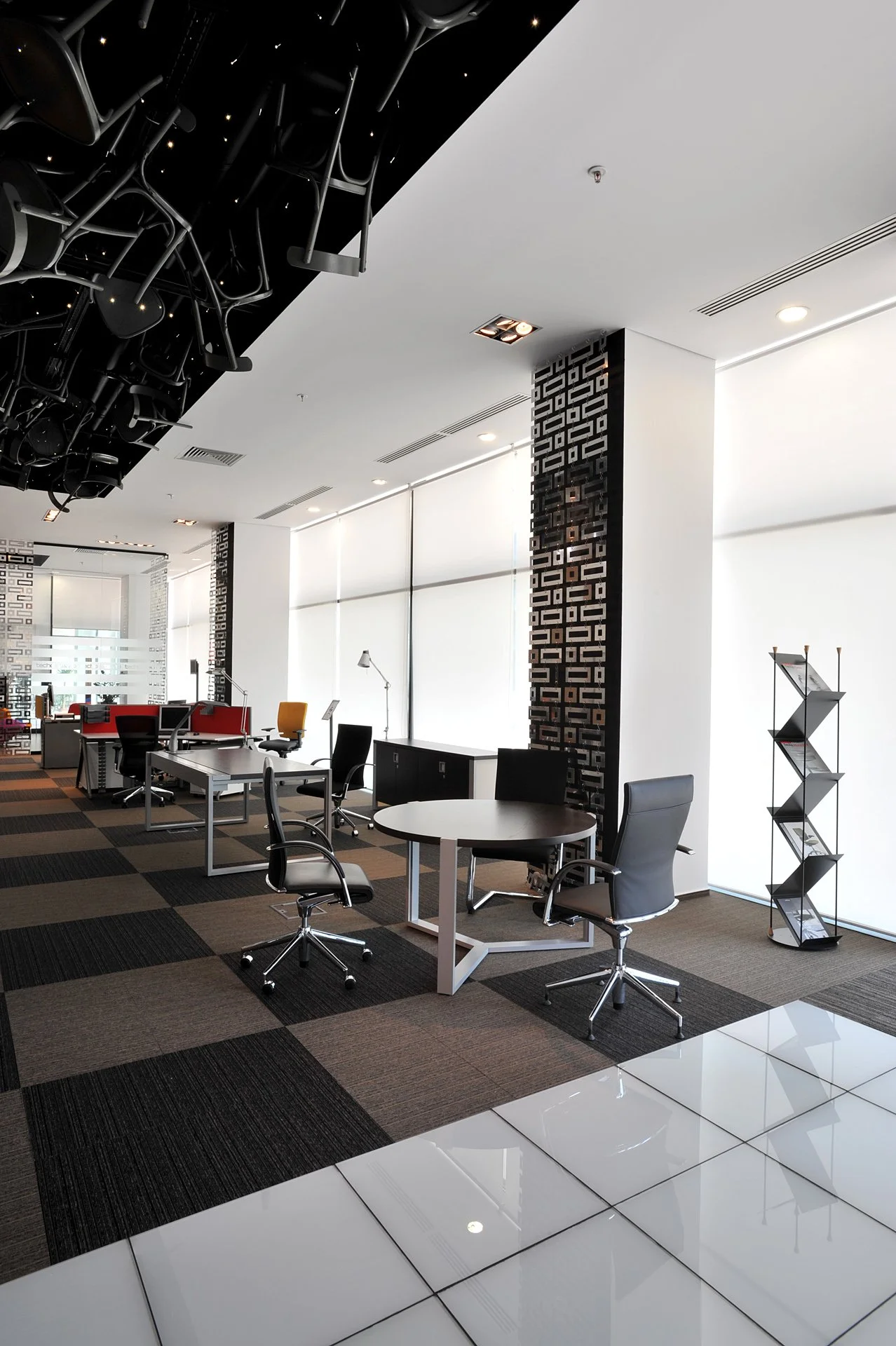 Empty modern office space with desks, chairs, and large windows with blinds.