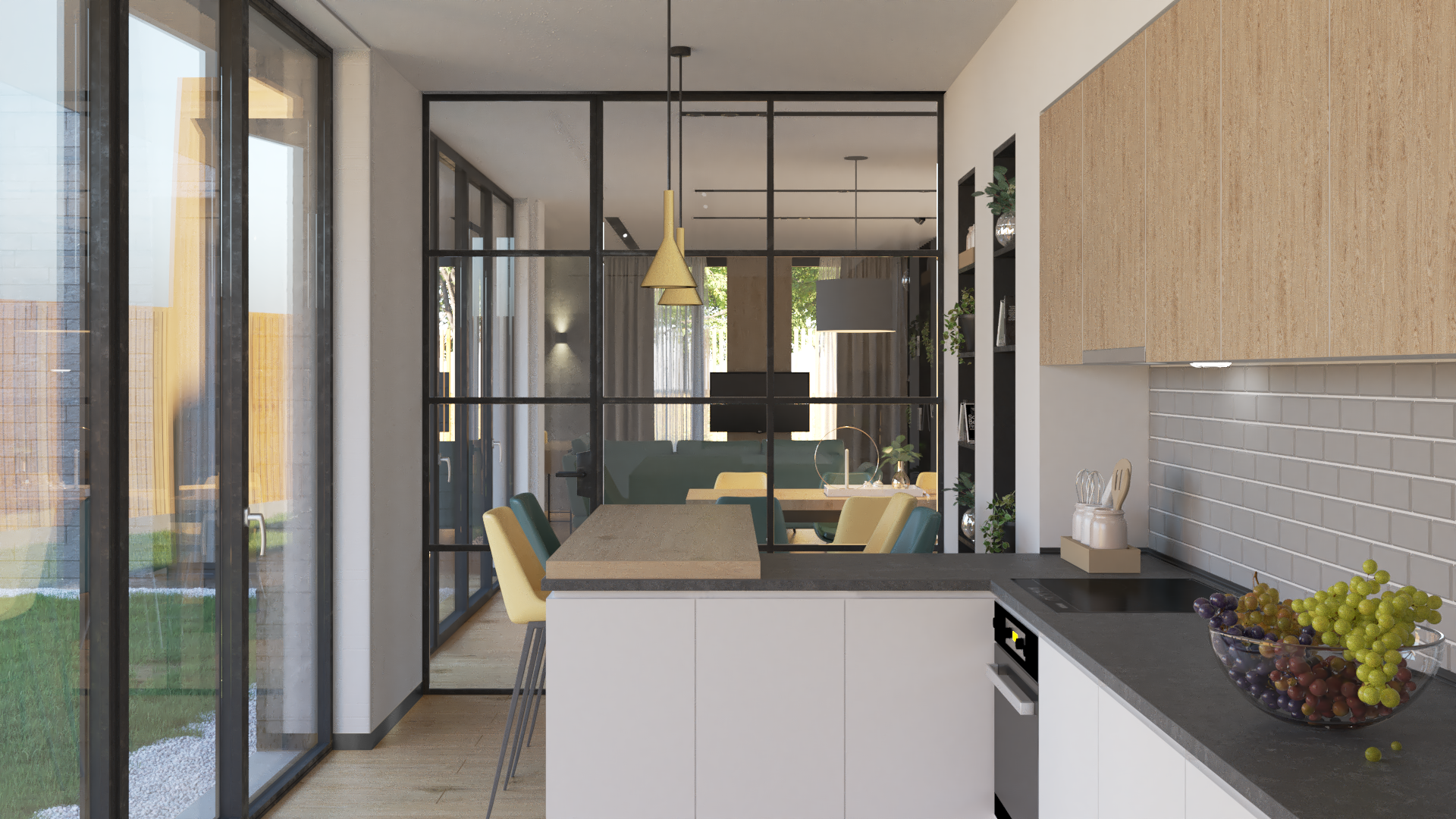 Modern open-plan kitchen with a black-framed glass partition separating the kitchen from the dining and living areas, featuring a bowl of mixed grapes on the black countertop.