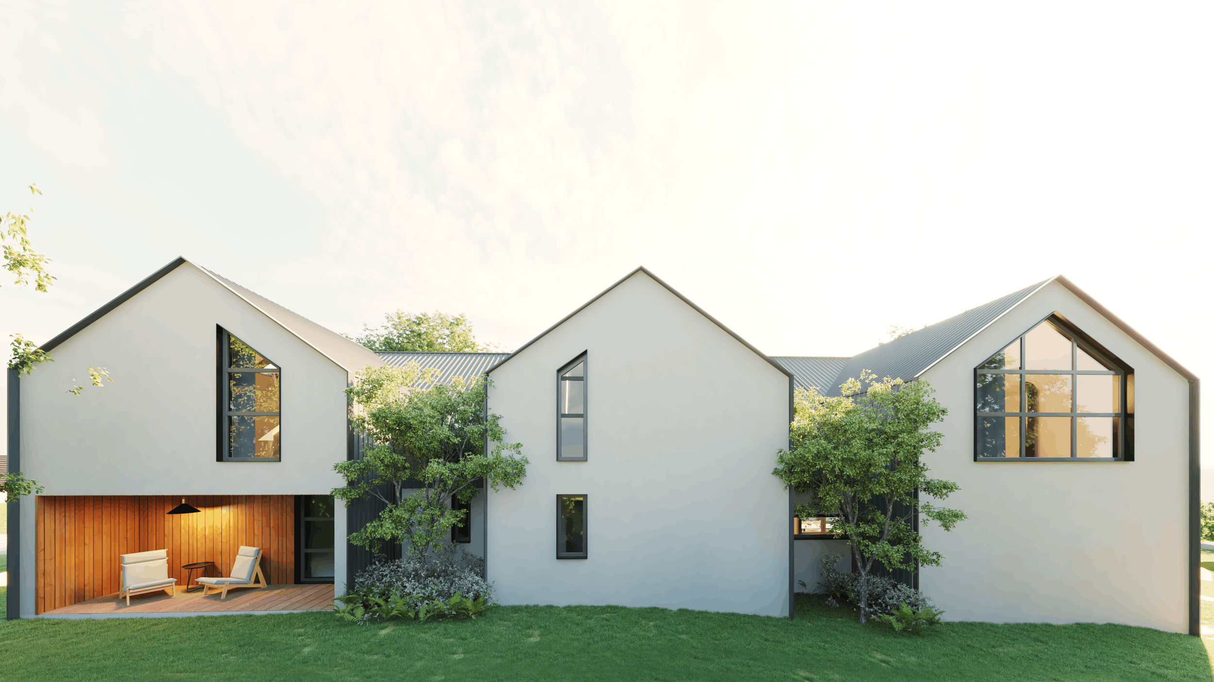 Modern white house with large windows, surrounded by greenery and trees, with a small outdoor seating area with chairs and a table.