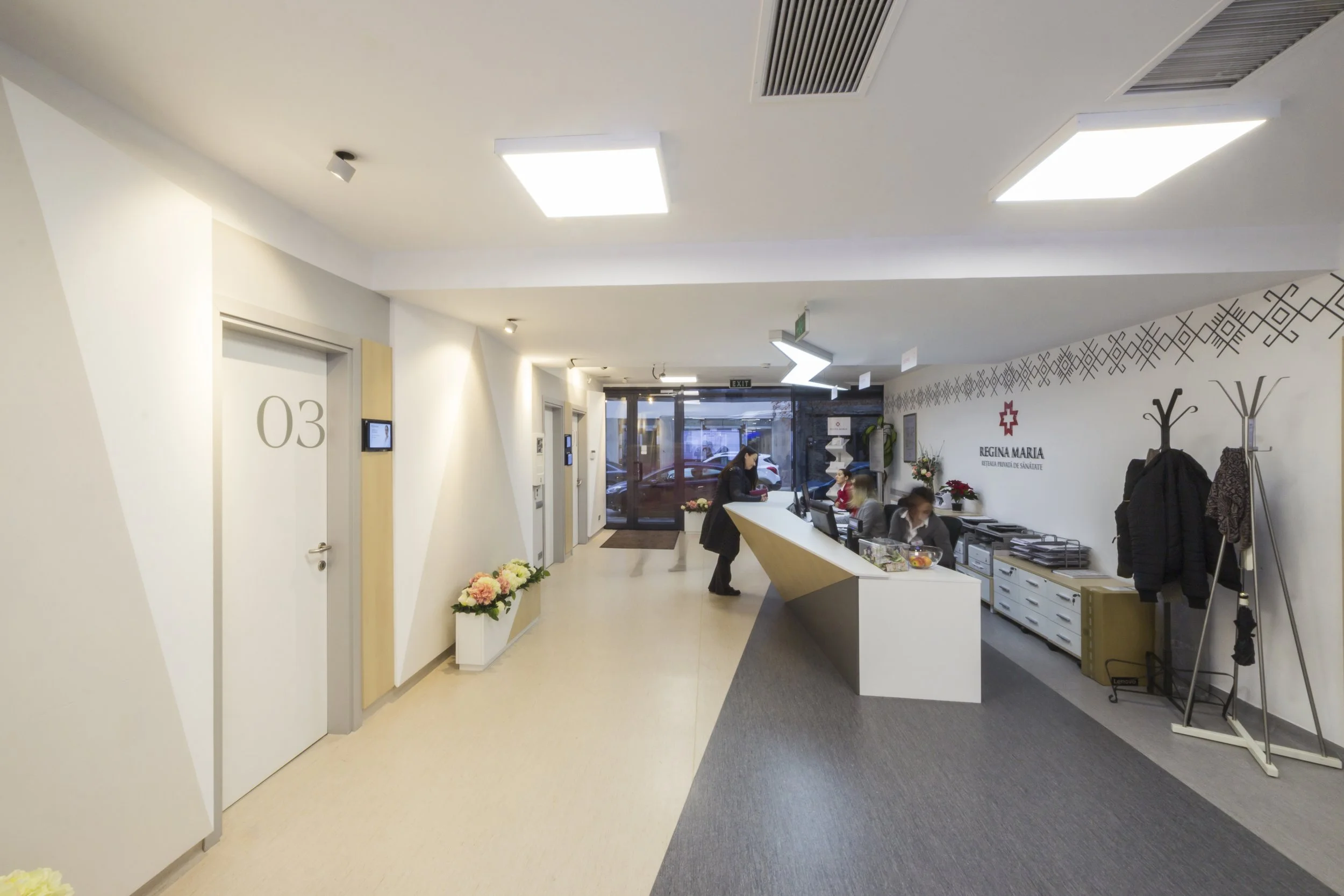 Medical clinic reception area with staff at the front desk and health-related signage.