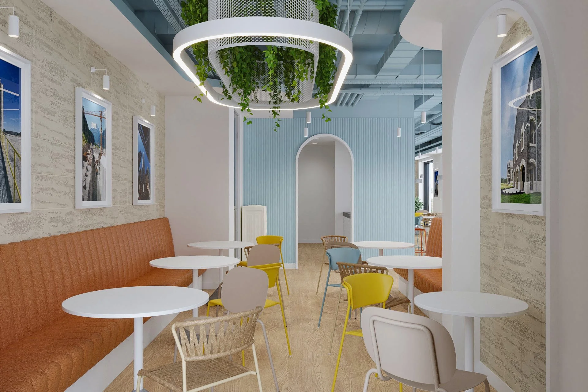 Bright cafe interior with white round tables, colorful chairs, orange booth seating, framed landscape photos on textured walls, and a ceiling decoration with hanging greenery.