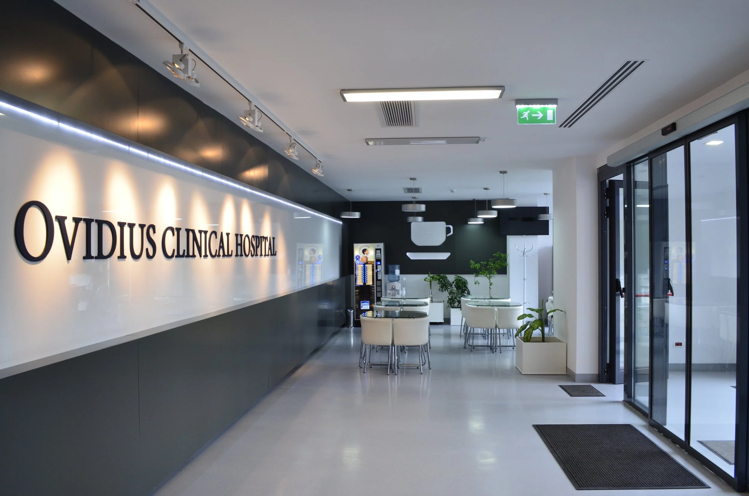 Reception area of Ovidius Clinical Hospital with seating, plants, vending machines, and hospital signage.