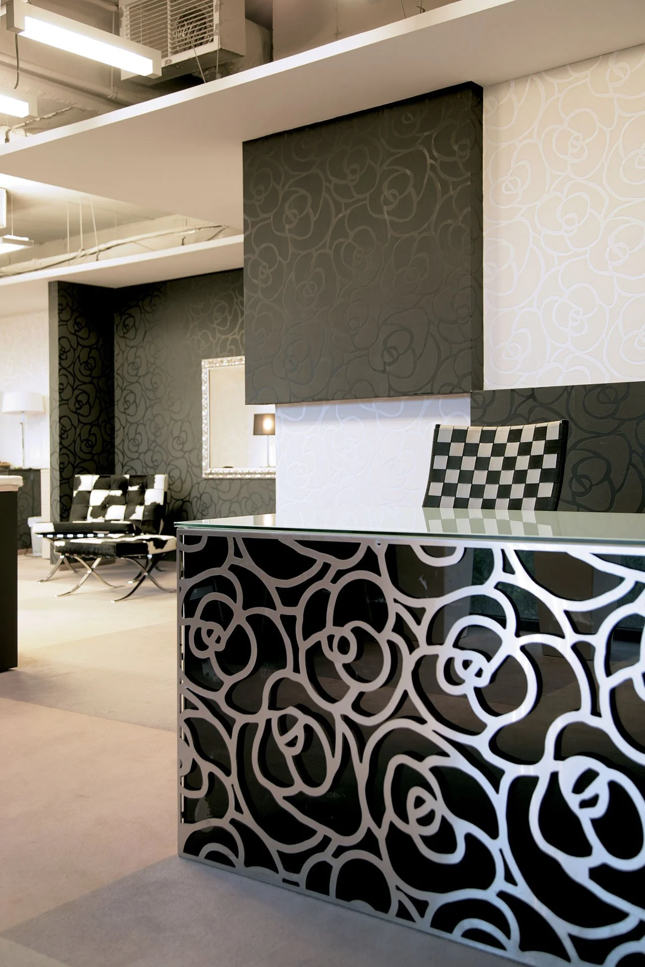 Modern office reception area with black and white floral pattern decor, checkered chairs, and a mirror