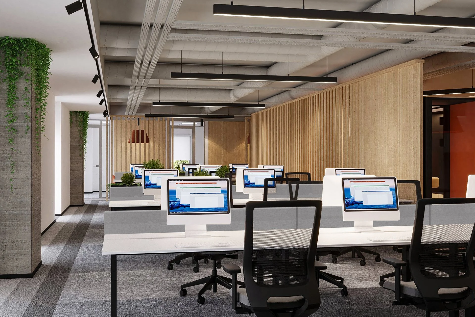 Modern office with multiple workstations, each with a computer monitor, black office chairs, and green plants, separated by wooden dividers, with exposed ceiling pipes and hanging lighting fixtures.