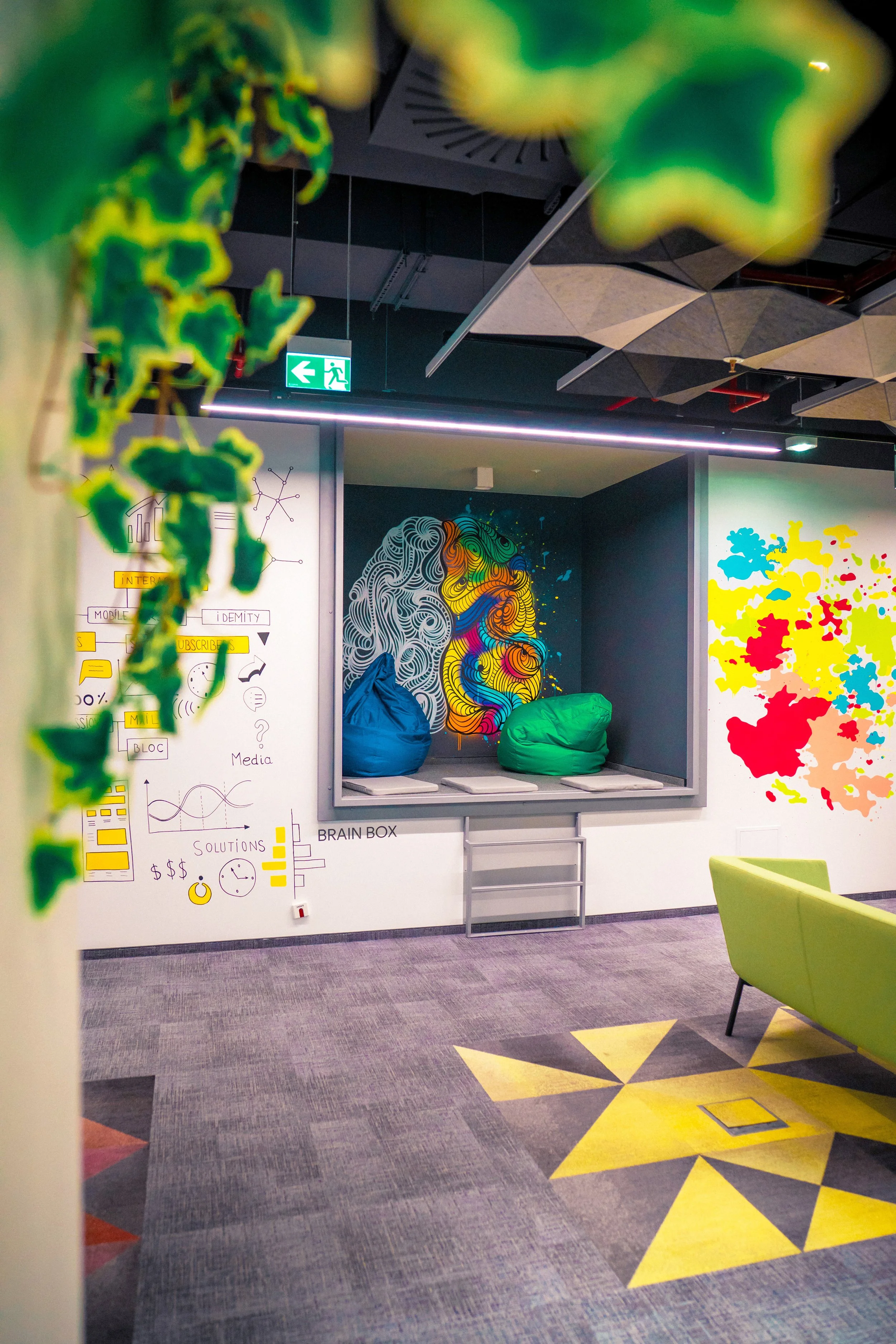 Colorful modern office lounge area with bean bags, abstract wall art, and vibrant wall paintings.