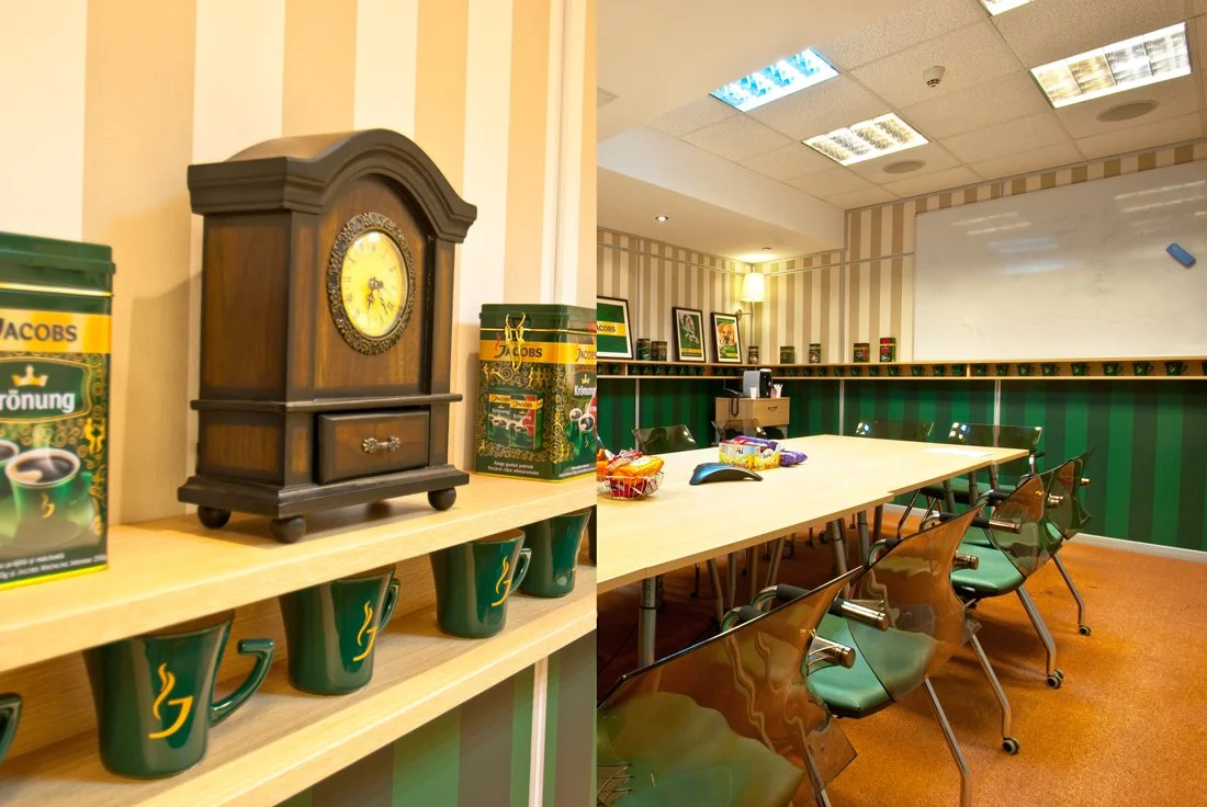 Conference room with green cups, a wooden clock, board game boxes, and a whiteboard.