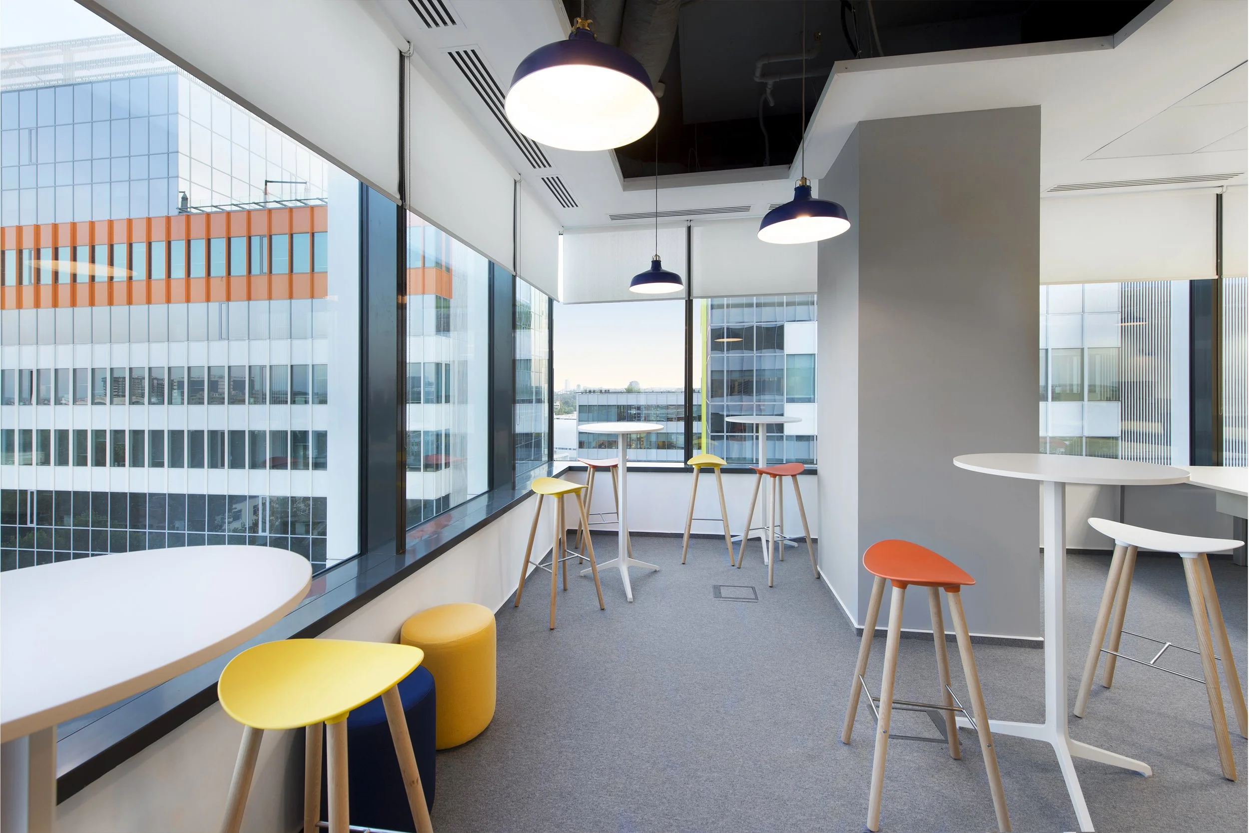 Empty modern office lounge with high tables, stools, and large windows with city view
