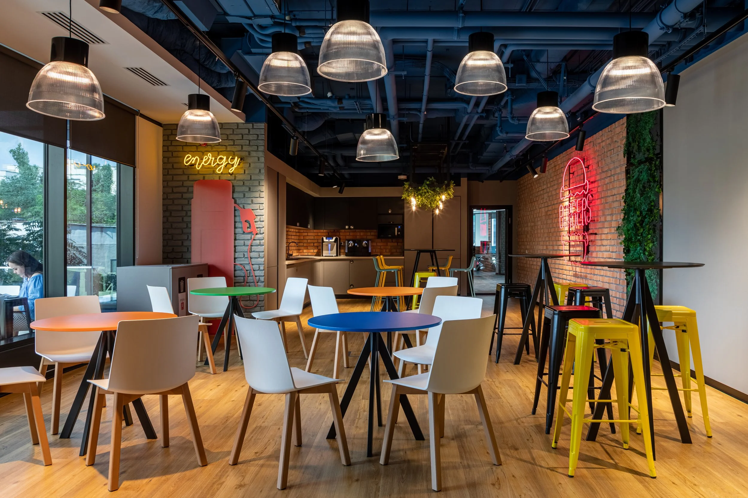 Colorful modern cafe with round tables, white and yellow chairs, and brick wall decor with neon signs