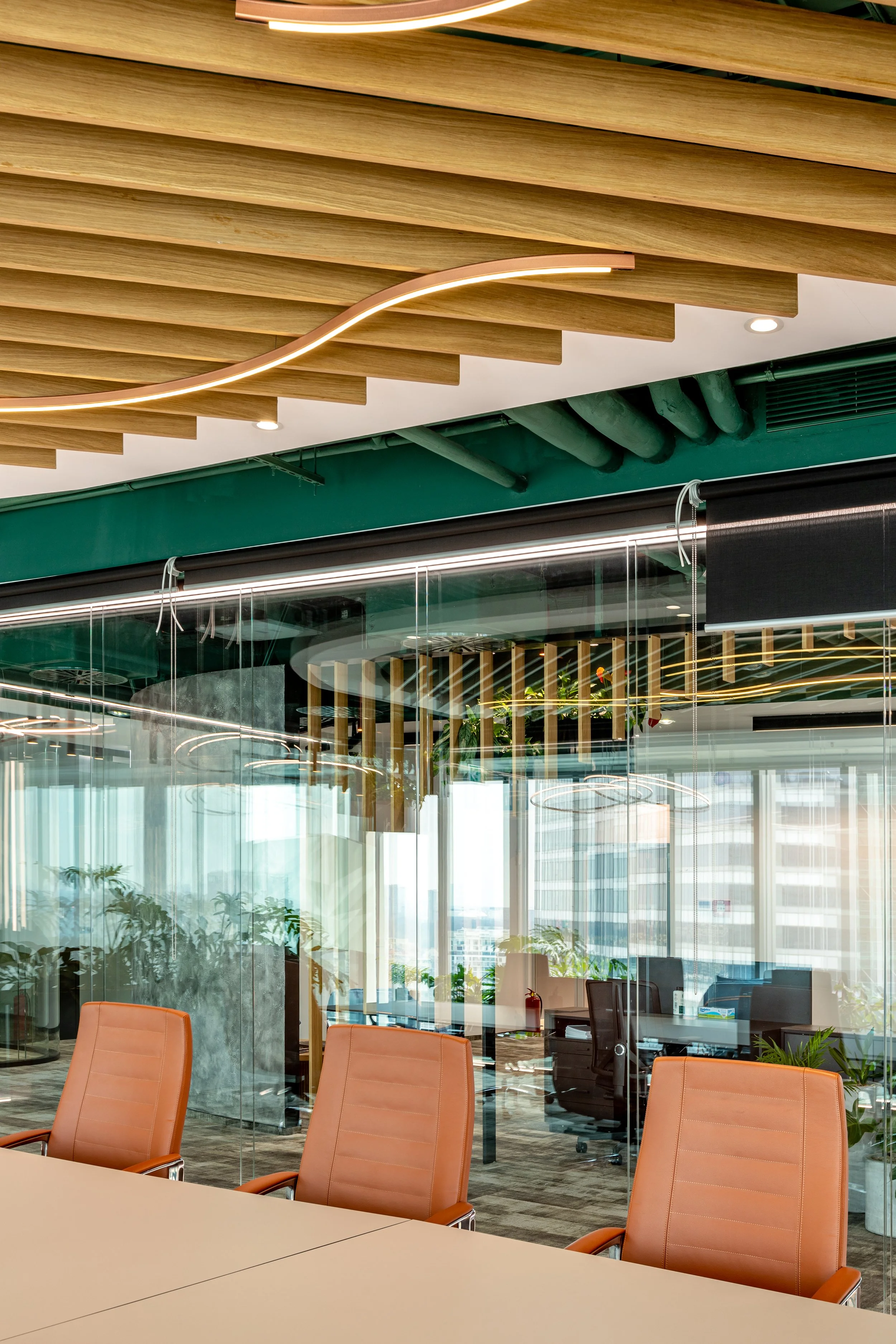 Modern conference room with orange chairs, glass partition, and wooden ceiling panels with built-in lighting inside an office building.