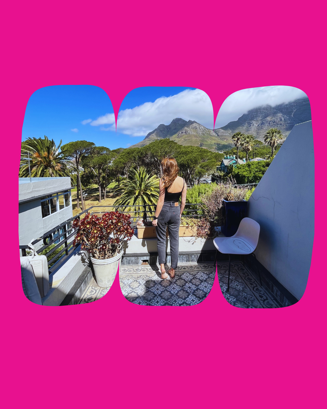 Woman standing on a balcony overlooking a lush landscape with trees, mountains, and a blue sky, with pink graphic overlay.