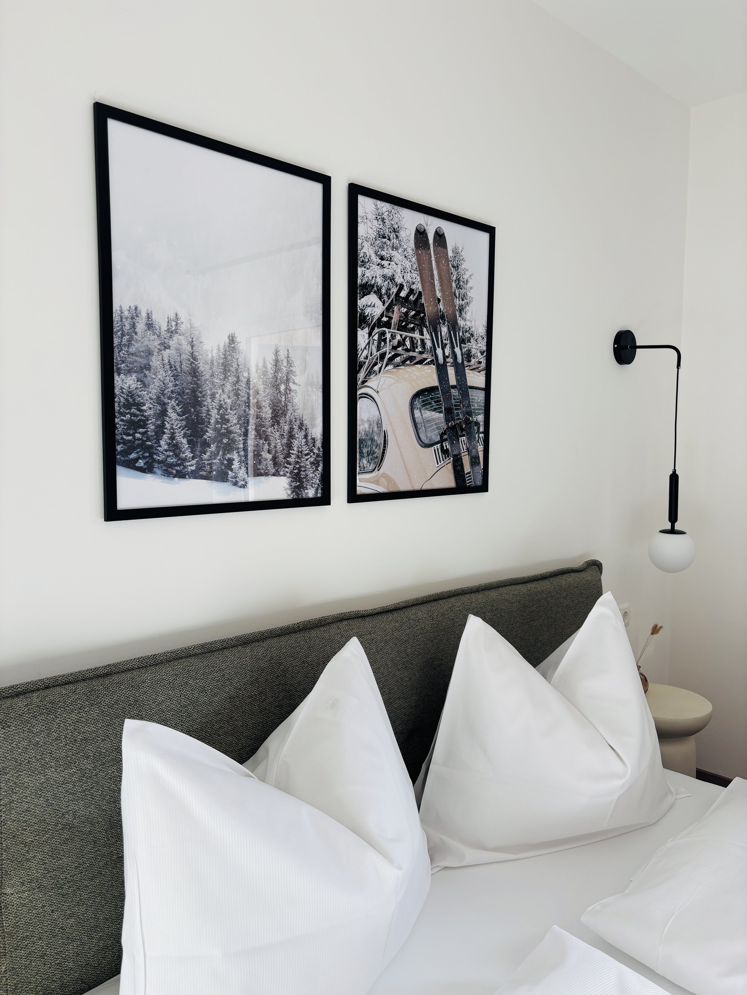 Bilder von verschneiten Winterlandschaften mit Bäumen und Skiern auf einem Auto, Fotografien hängen an der Wand.