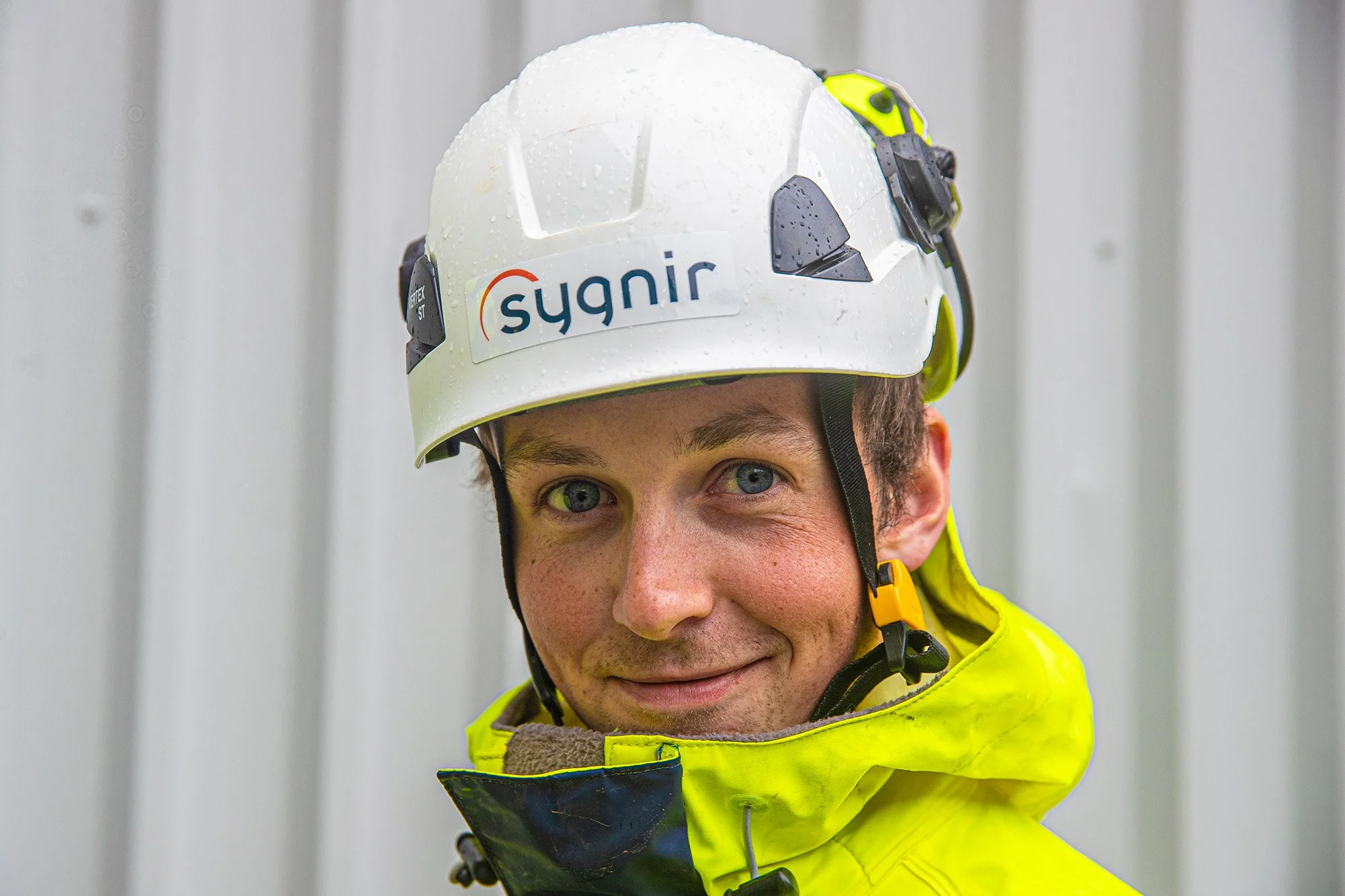 Smilande montør med hjelm og arbeidsklede