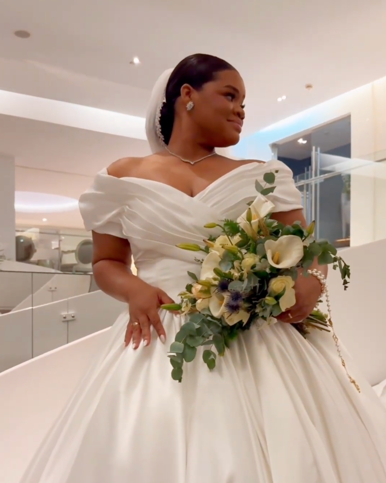 Uma mulher em um vestido de casamento branco segurando um buquê de flores.