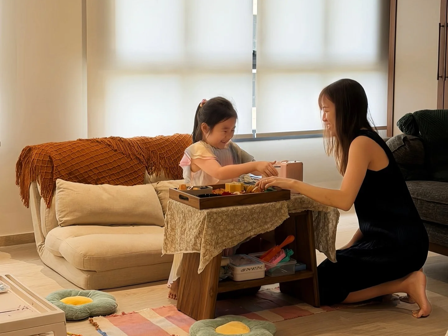 A woman and a young girl playing a board game together in a living room.