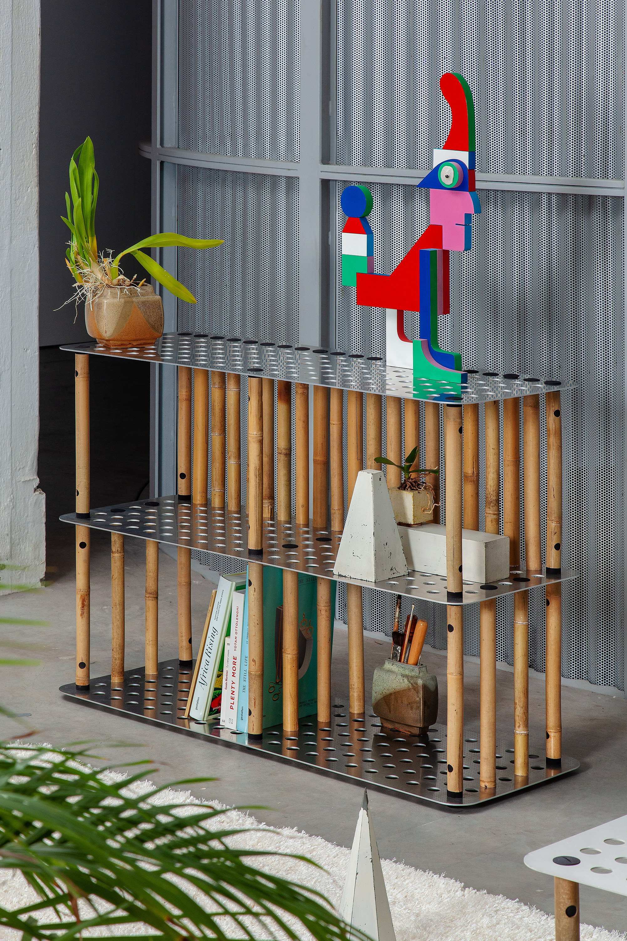 Decorative shelf with books, plants, and a colorful abstract sculpture in a modern interior.