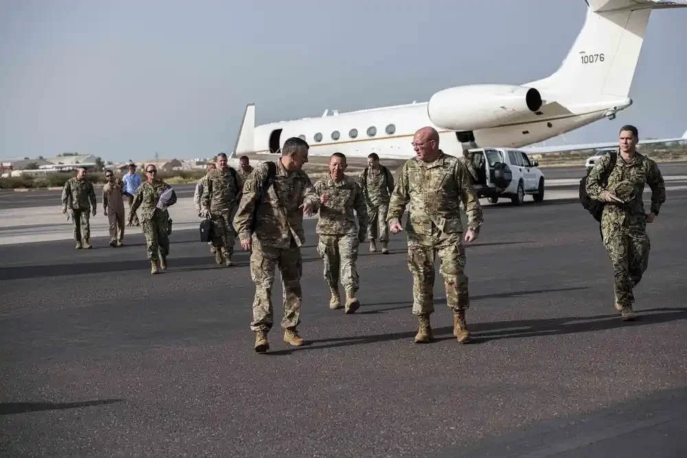 Military personnel walking on an airfield near a private jet aircraft.