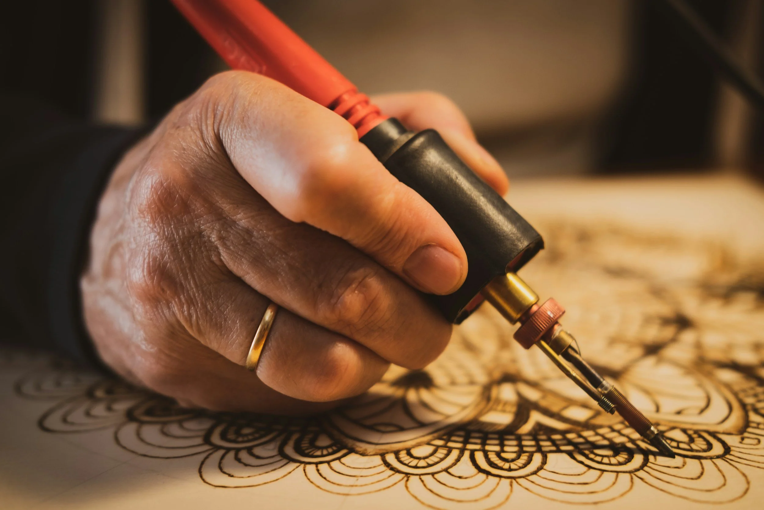 Close up of pyrography tool in detailed traditional artwork
