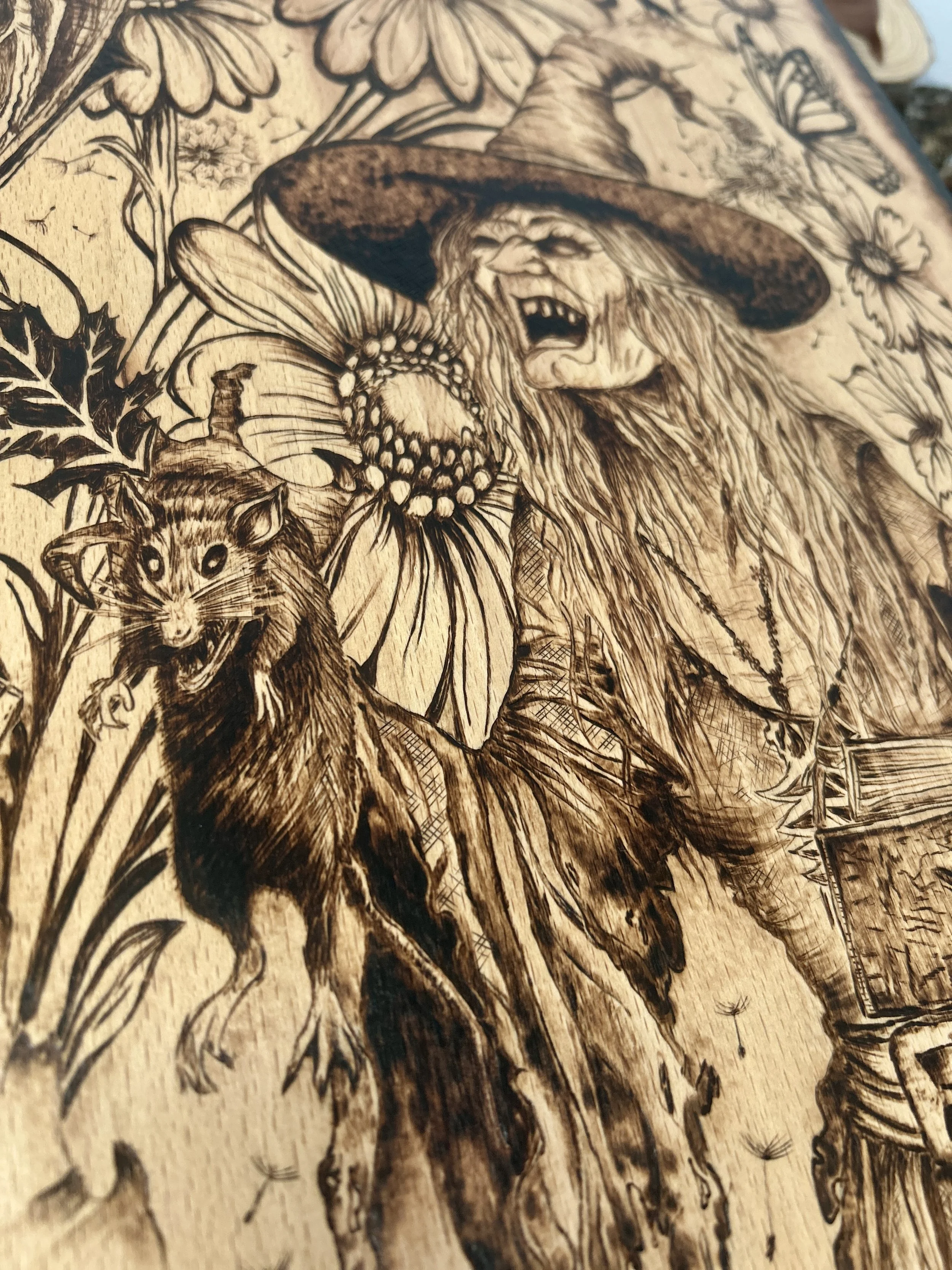 Detailed portrait of a cackling witch with long hair and a pointed hat, holding a cat, rendered in dark wood-burned tones.