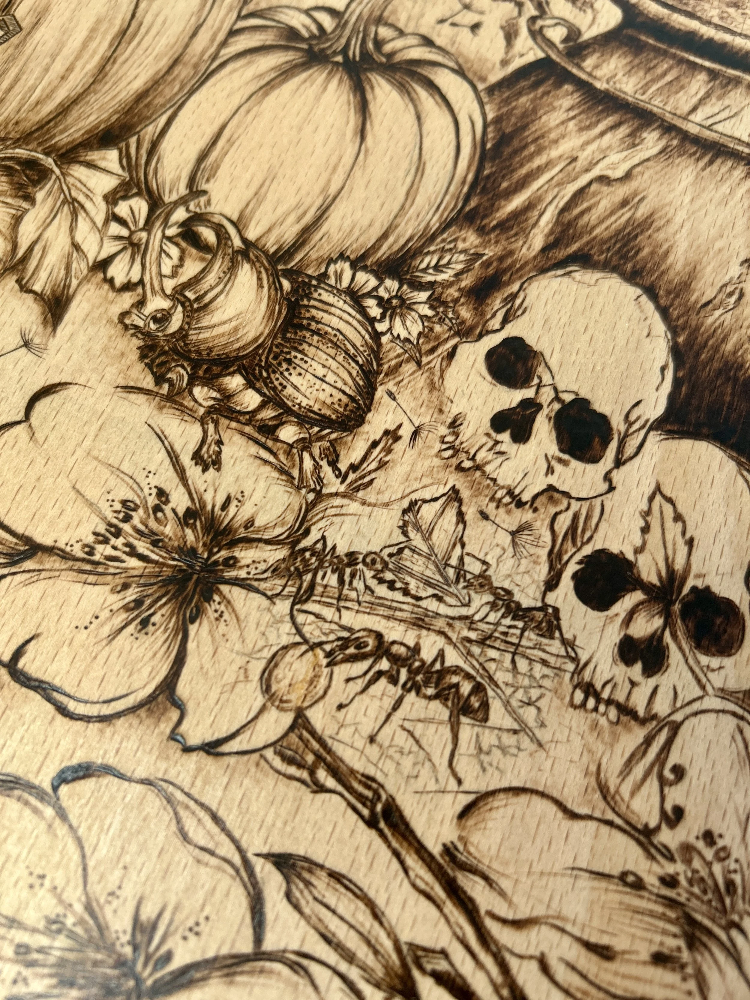 Macro shot of the lower artwork section, highlighting several small skulls, flowers, and the base of a pumpkin.