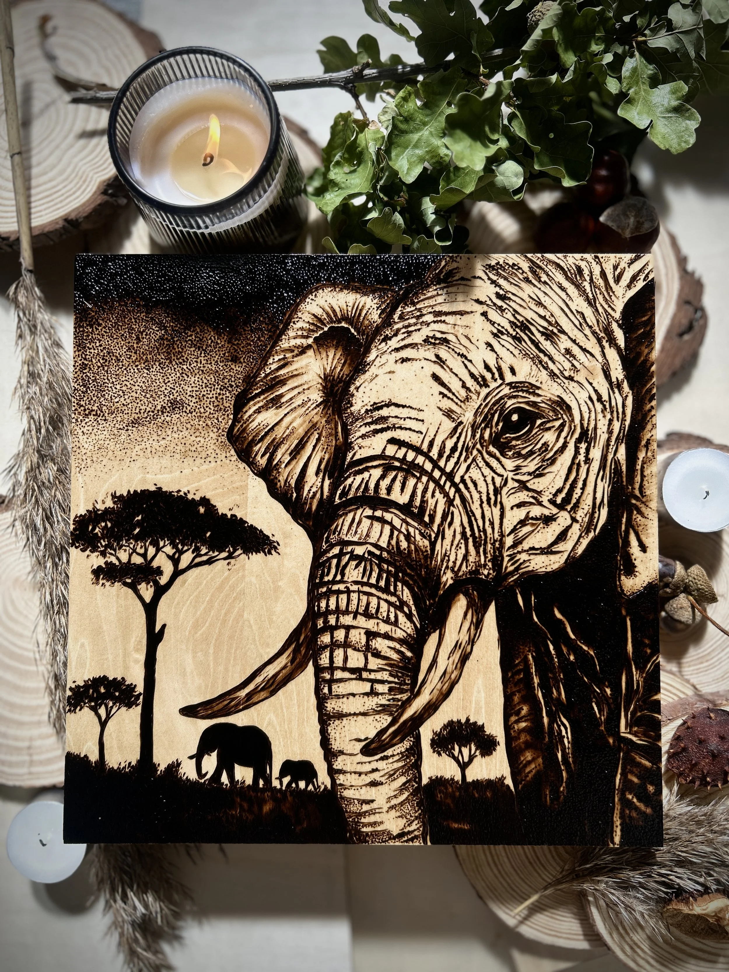 Wood-burned elephant artwork with bold lines, acacia trees, and African savanna elements.
