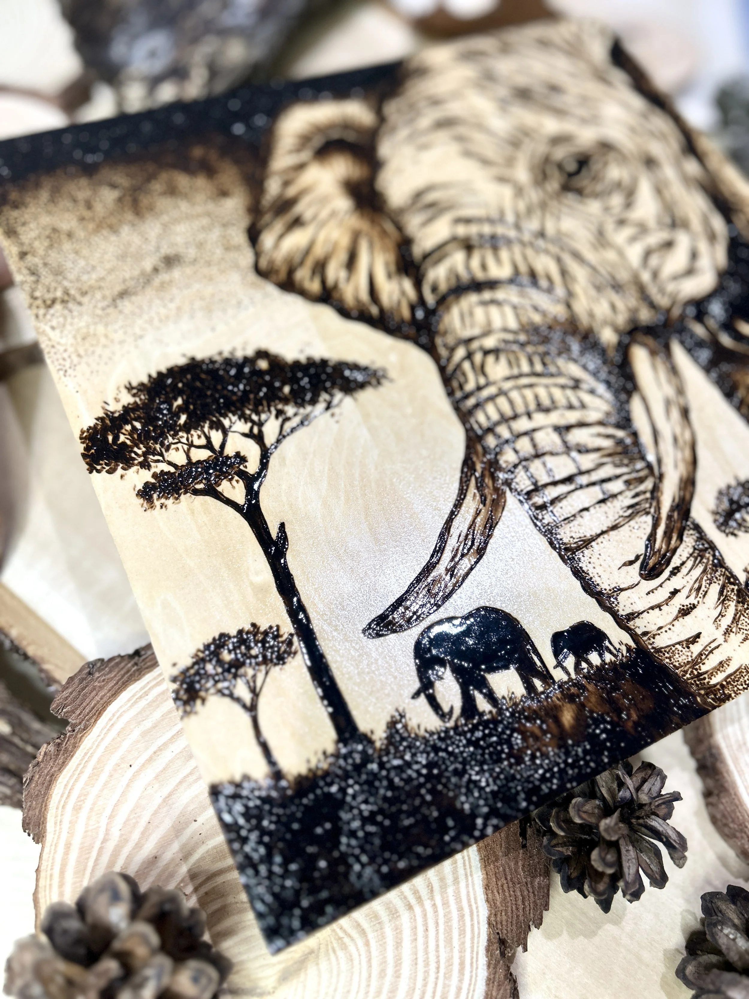 Collection of wood-burned pyrography artworks showcasing handcrafted fantasy art in unique, artisan, one-of-a-kind designs and decor, featuring detailed Savanna Reverie elephant scenes on natural wood