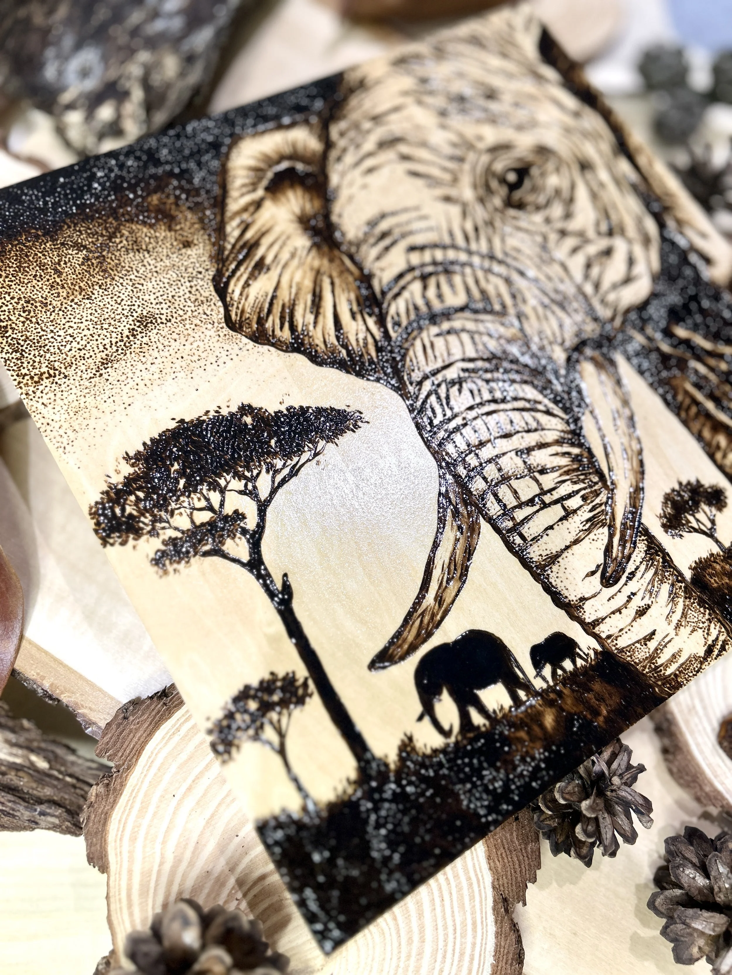 Collection of wood-burned pyrography artworks showcasing handcrafted fantasy art in unique, artisan, one-of-a-kind designs and decor, featuring detailed Savanna Reverie elephant scenes on natural wood