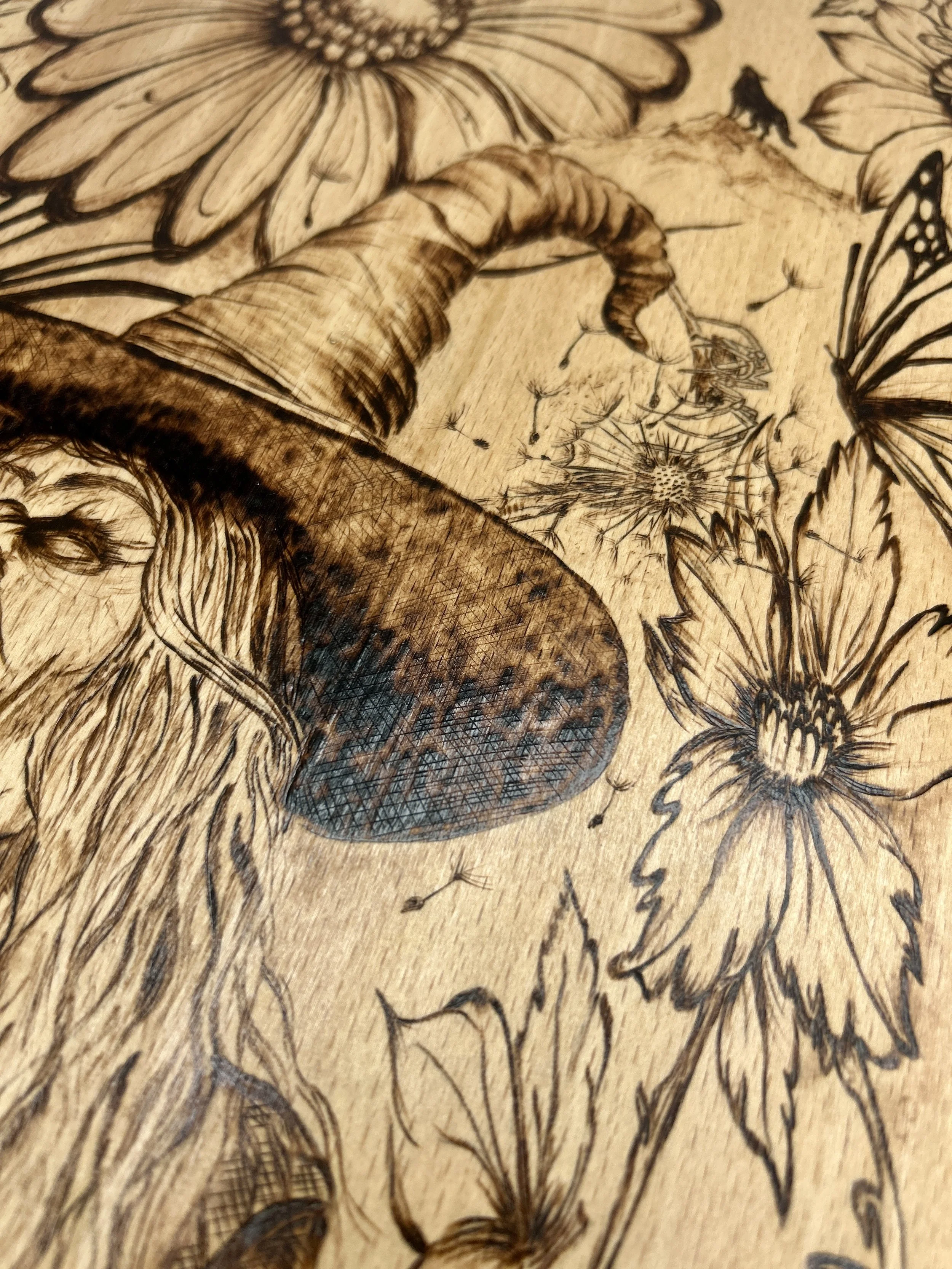 Close-up of the top of the witch's hat nestled among flowers, showcasing the fine shading used to create a 3D effect on the wood.