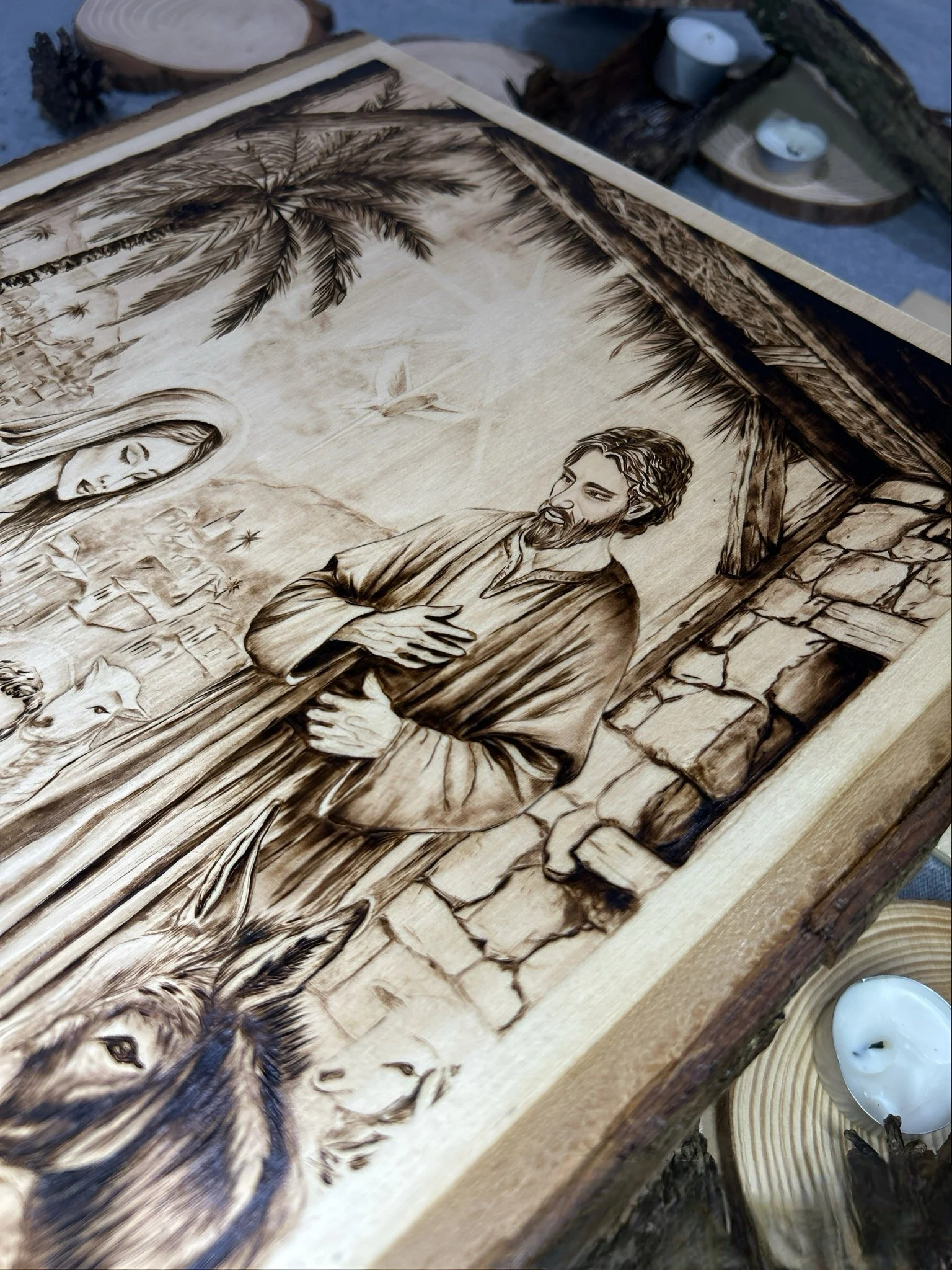 Close-up of woodburned robe texture in Stable Of Grace pyrography on solid hardwood.