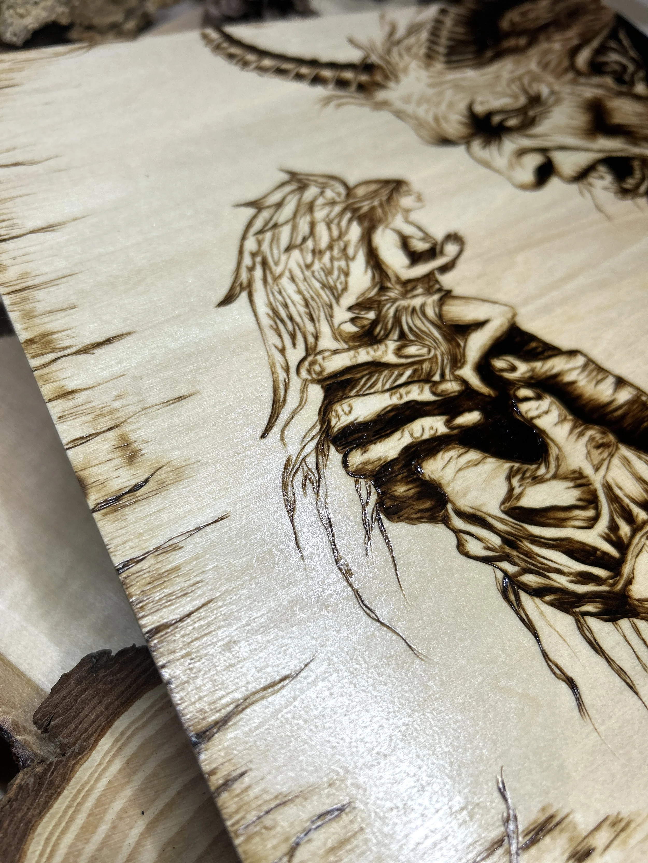 Collection of wood-burned pyrography artworks featuring angels and demons, showcasing handcrafted fantasy art in unique, artisan, one-of-a-kind designs and decor