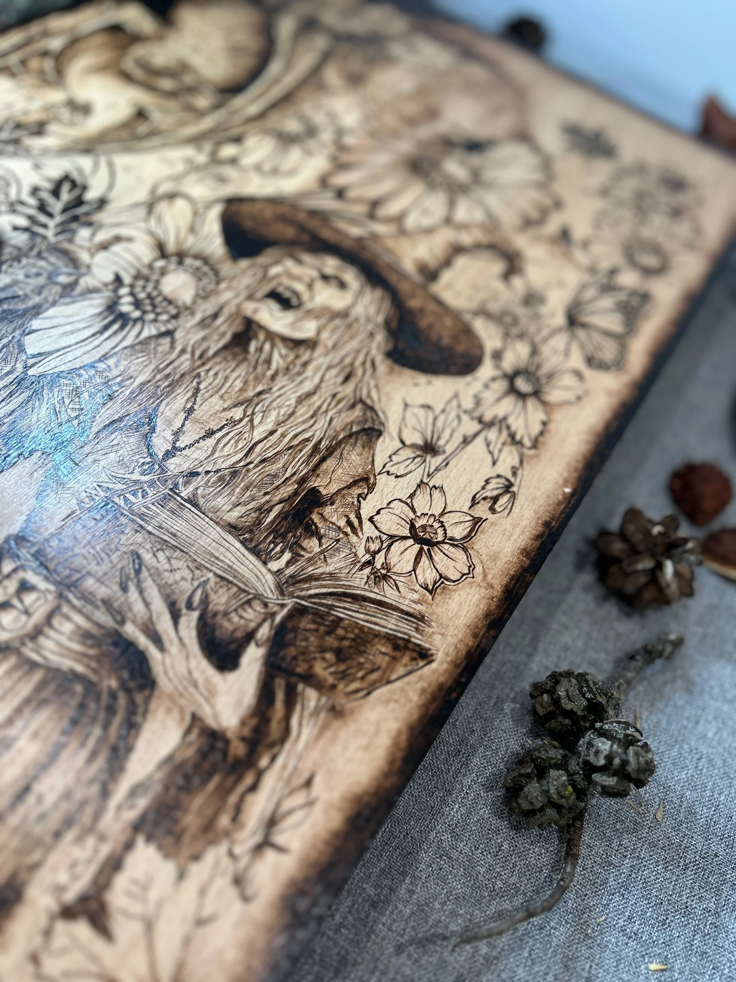 High-angle view of The Darkest Wishes pyrography, highlighting layout of witch, skulls, and hidden natural details on solid hardwood