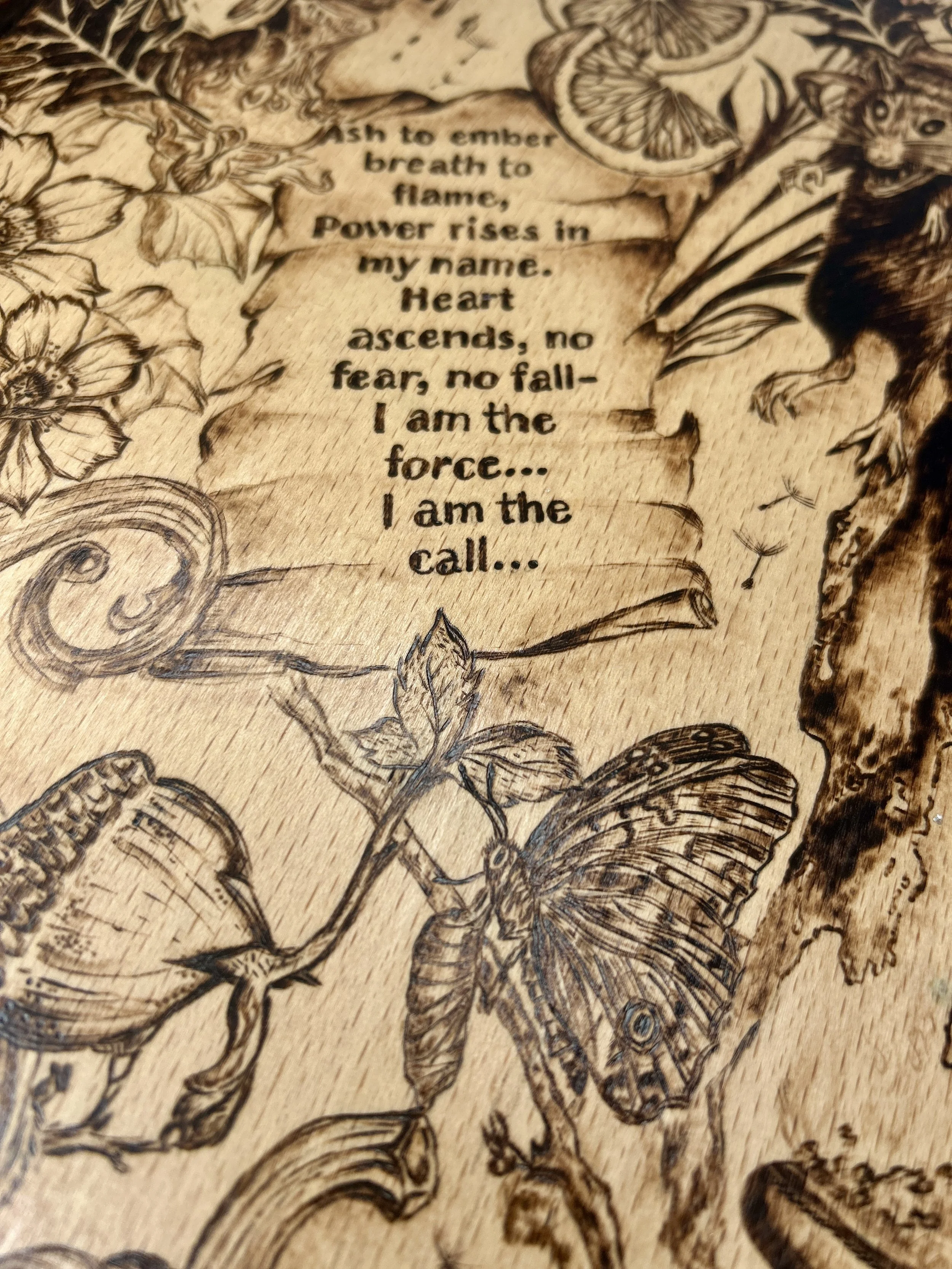 Macro shot of the parchment scroll, focusing on the burned poetic text and the decorative swirling patterns at the edges.