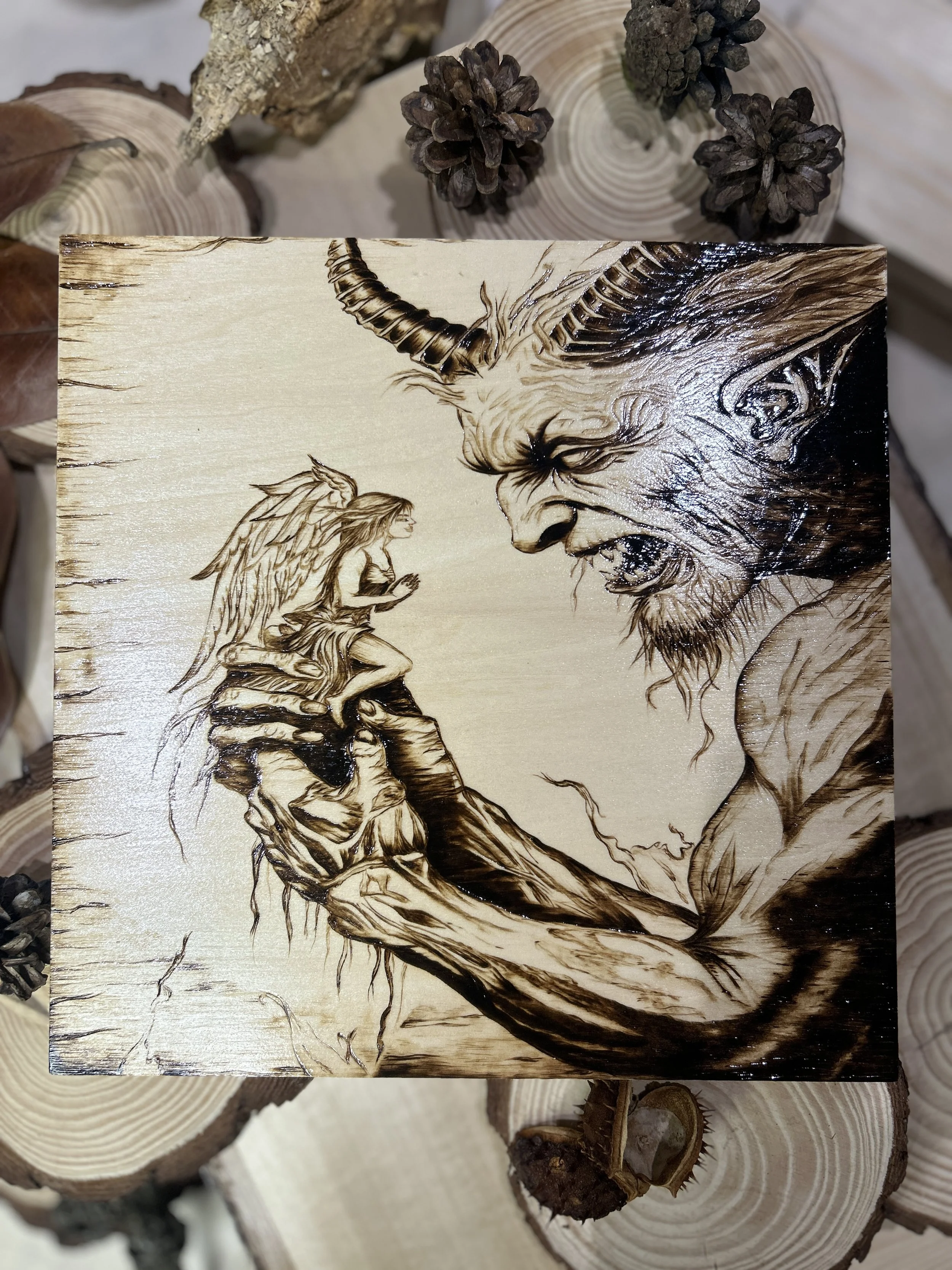Collection of wood-burned pyrography artworks featuring angels and demons, showcasing handcrafted fantasy art in unique, artisan, one-of-a-kind designs and decor