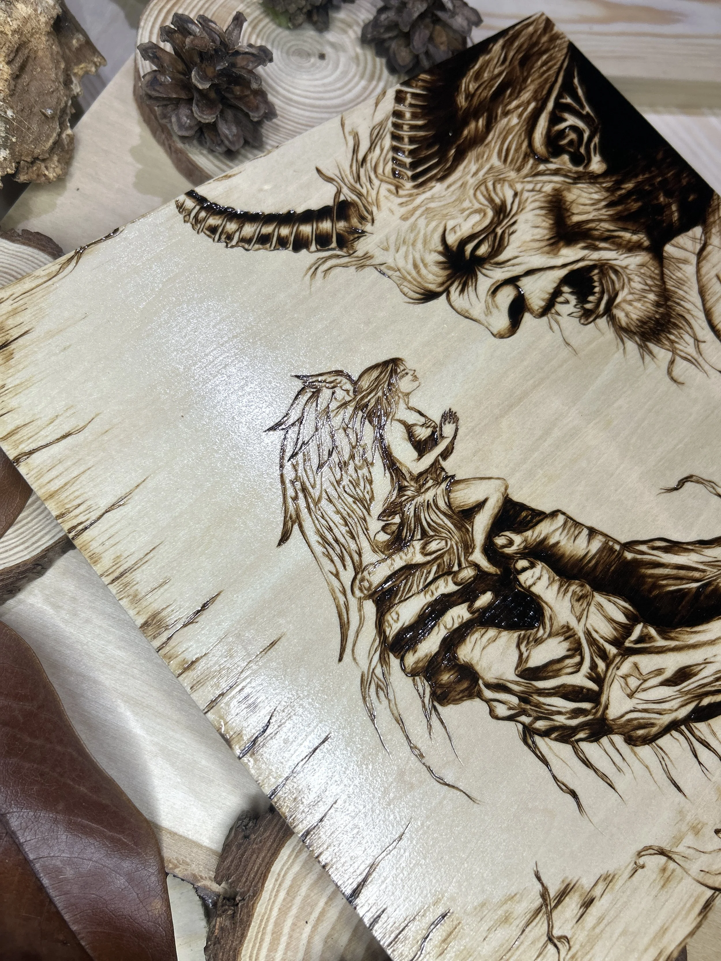 Collection of wood-burned pyrography artworks featuring angels and demons, showcasing handcrafted fantasy art in unique, artisan, one-of-a-kind designs and decor
