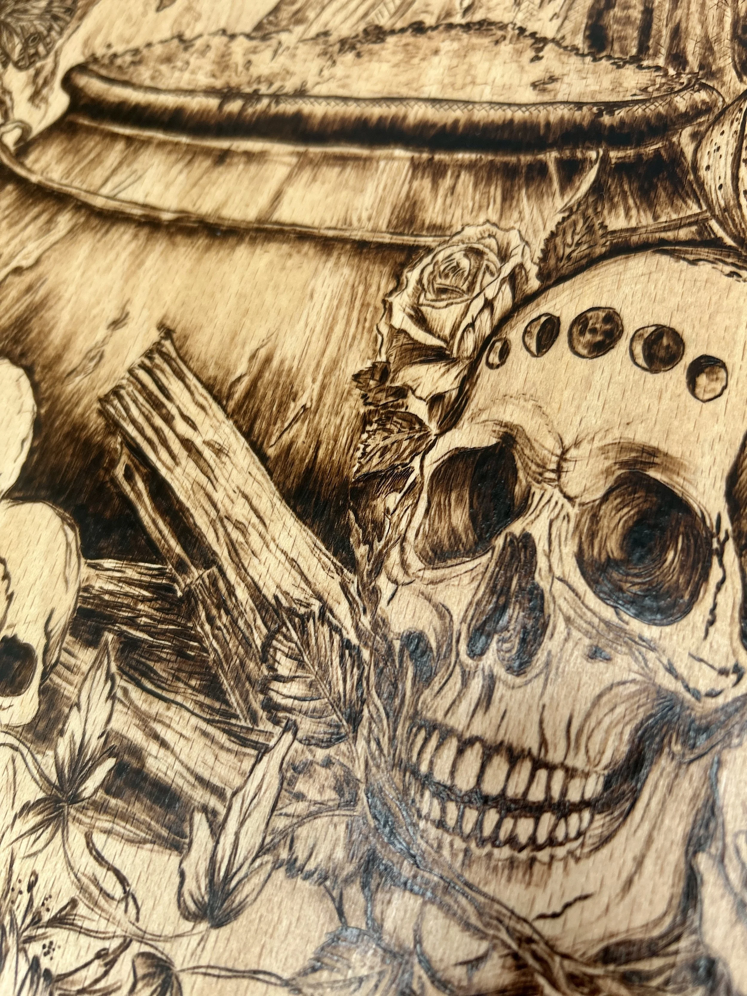 Lower section detail featuring the steaming cauldron, stacked firewood, and a human skull with lunar-cycle markings.