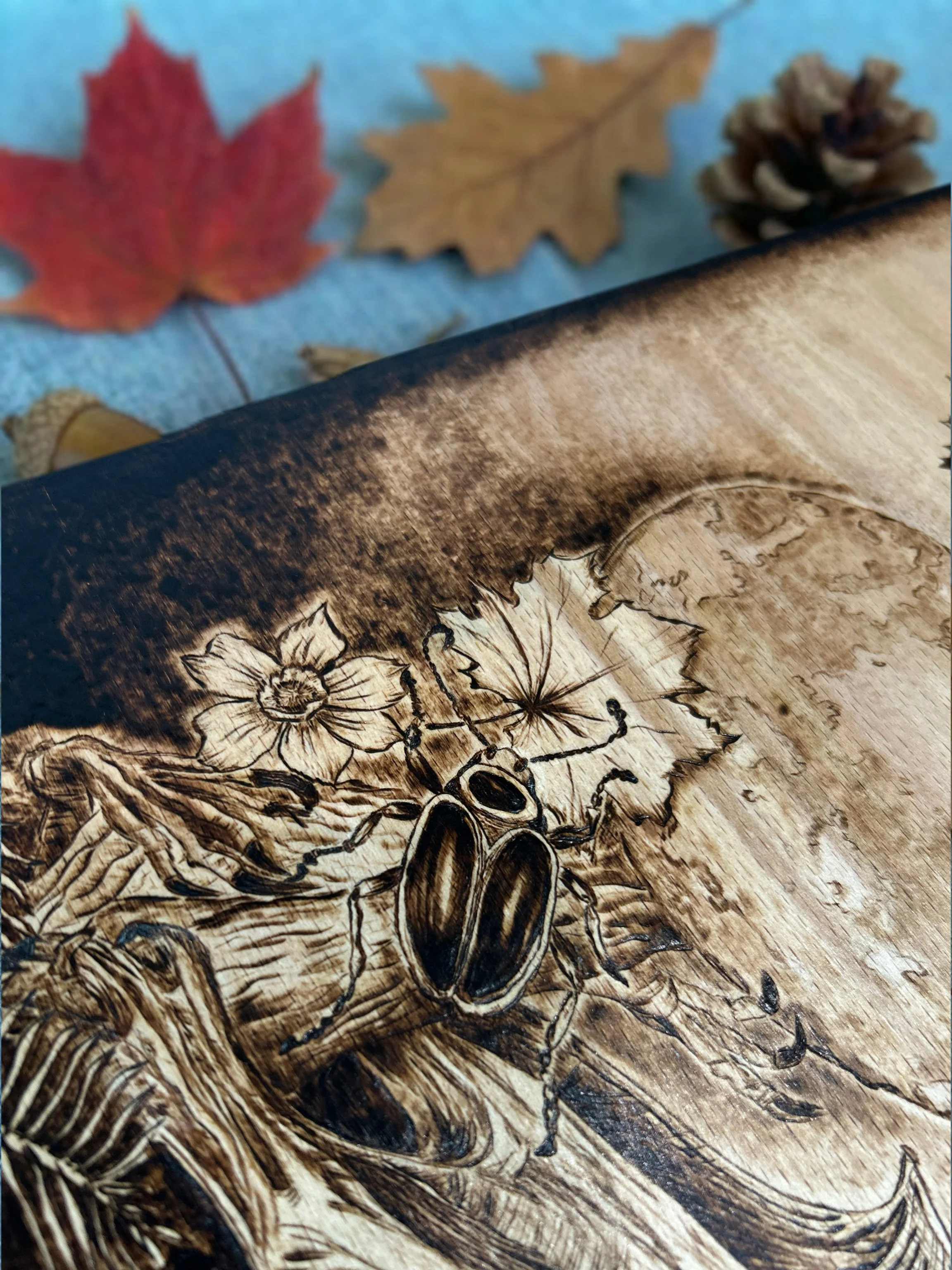Wood-burned beetle artwork with detailed leaves, flowers, and natural botanical elements.