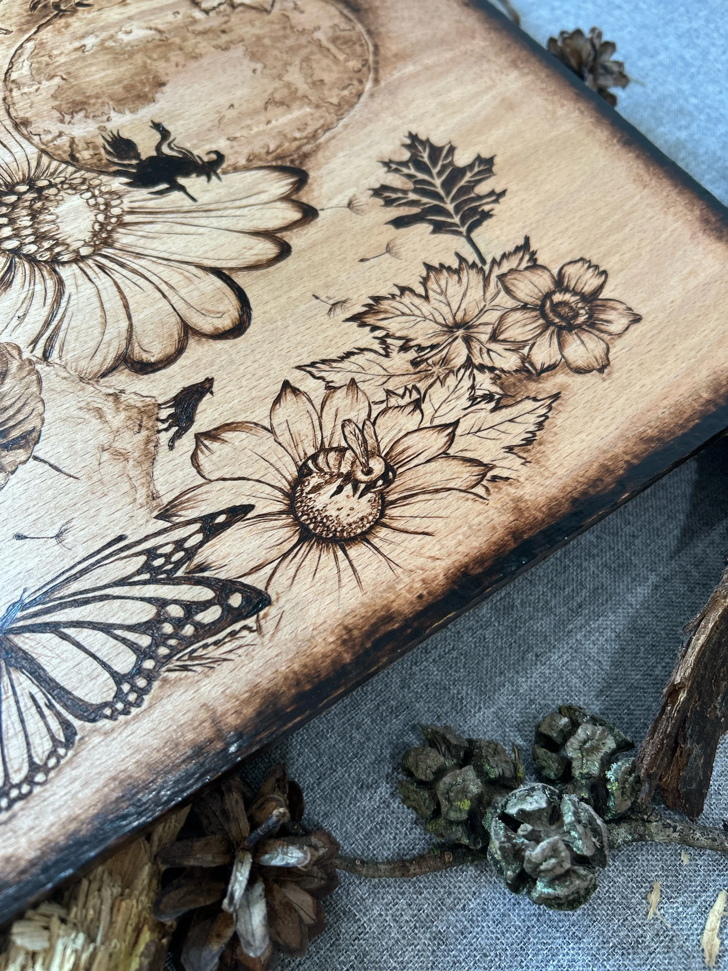 Close-up of daisy veins and butterfly wing patterns in The Darkest Wishes pyrography on solid hardwood timber.