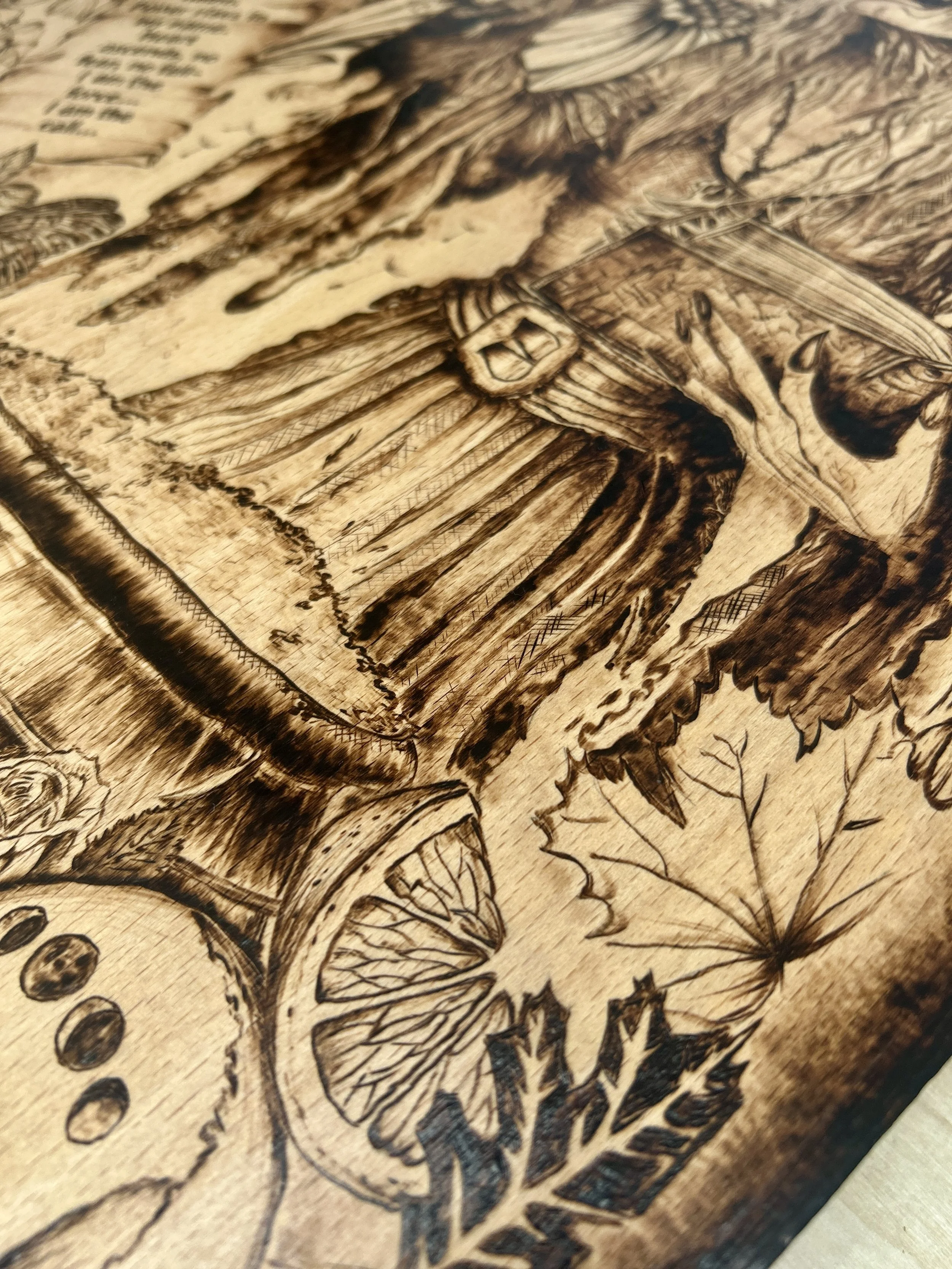 Side-angle close-up of a wood-burned witch showing the texture of her dress and the edge of the cauldron, emphasizing the depth of the pyrography.