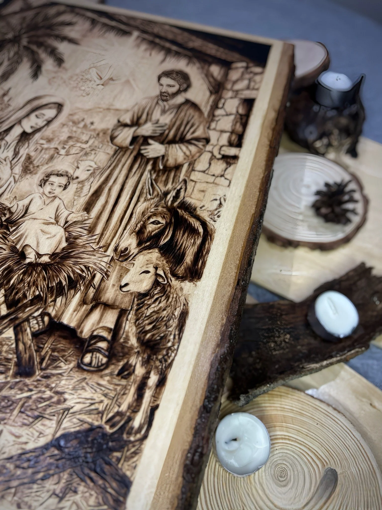Angled close-up of Stable Of Grace pyrography, showing detailed figures and wood grain integration