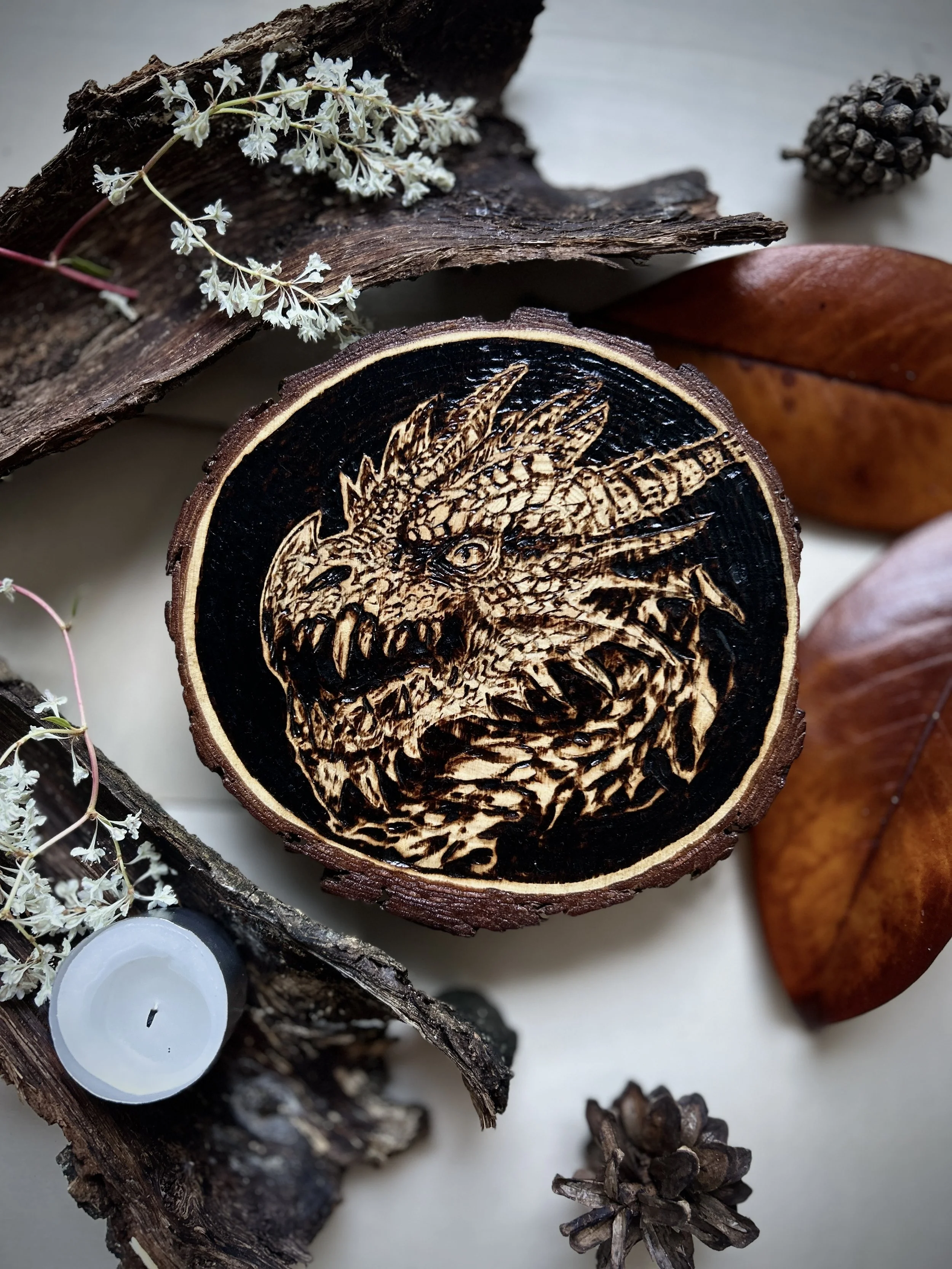 Wood-burned dragon artwork on a natural wooden slice with detailed scales and fantasy design.