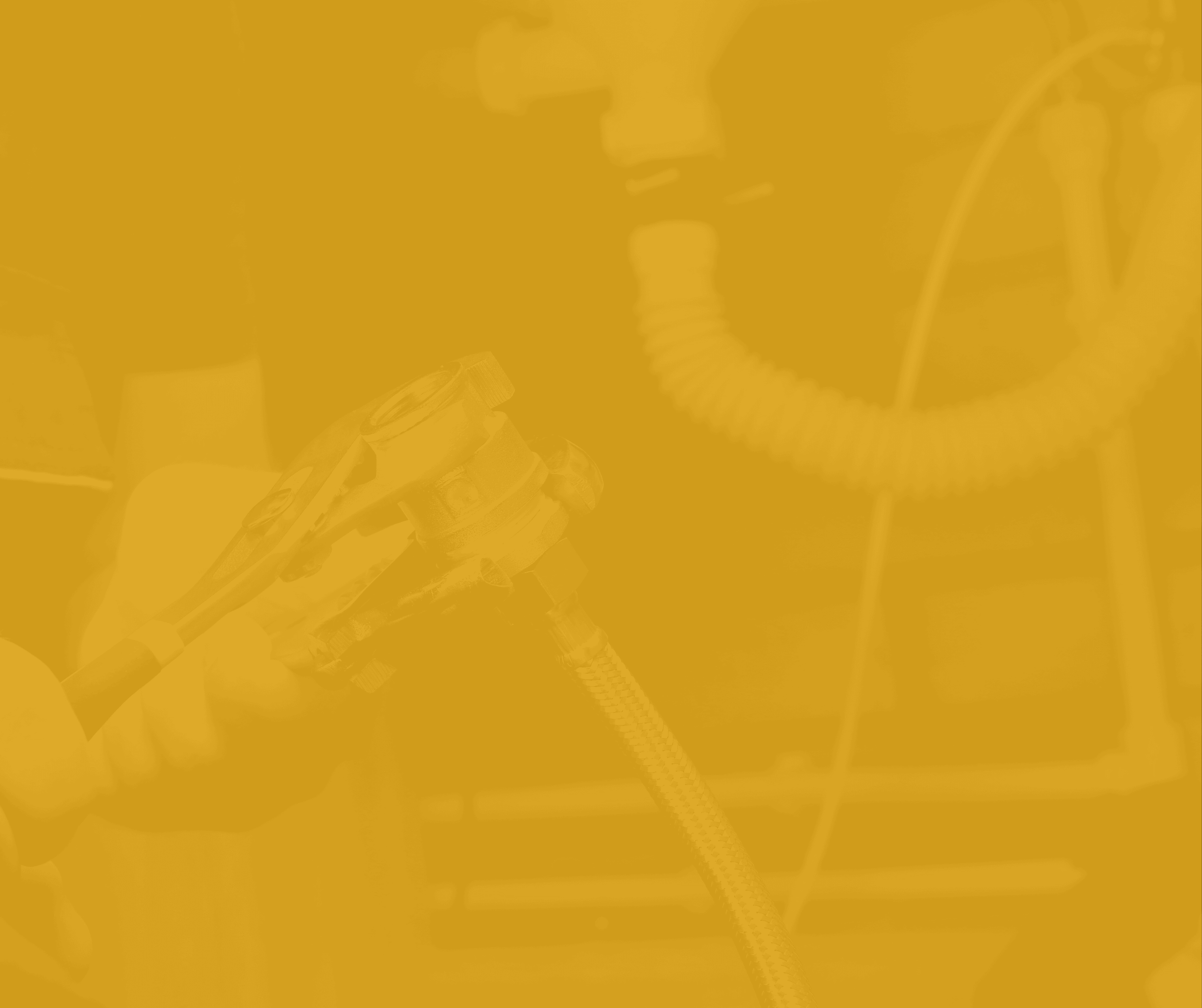 A person wearing gloves holding a showerhead with a hose, likely a plumber or maintenance worker repairing plumbing.