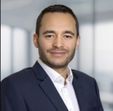 Porträt eines Mannes in Businesskleidung vor moderner Büroarchitektur.