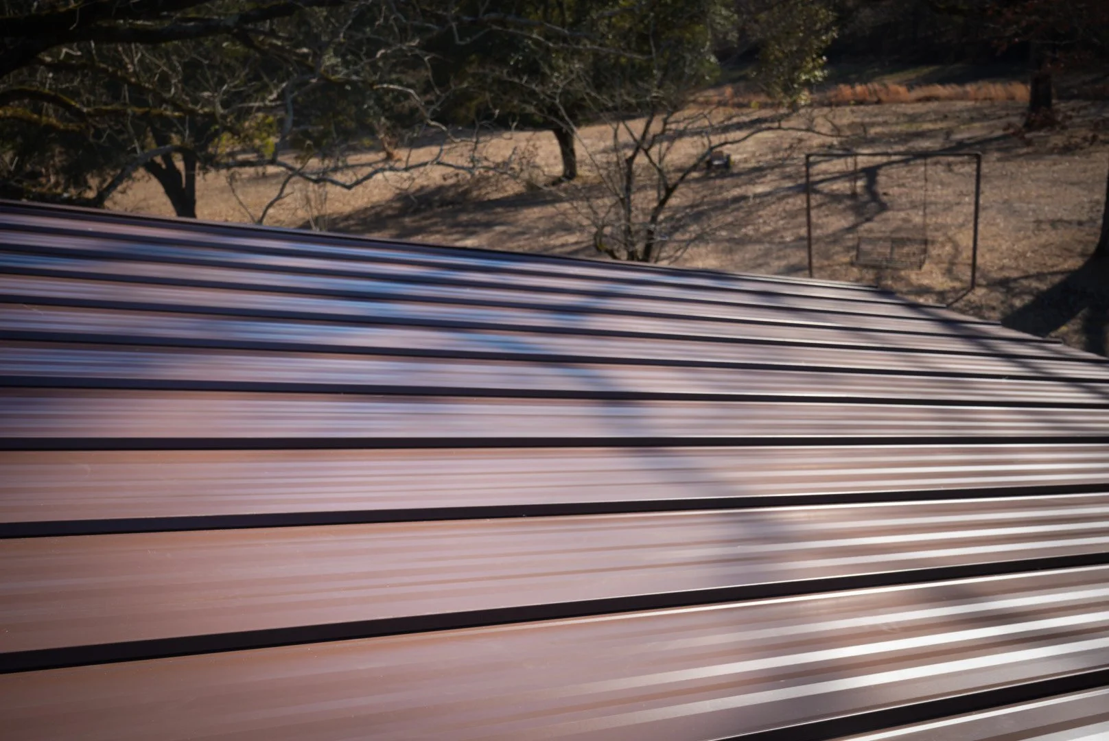 Blurred metallic roof with trees and a dry landscape in the background.