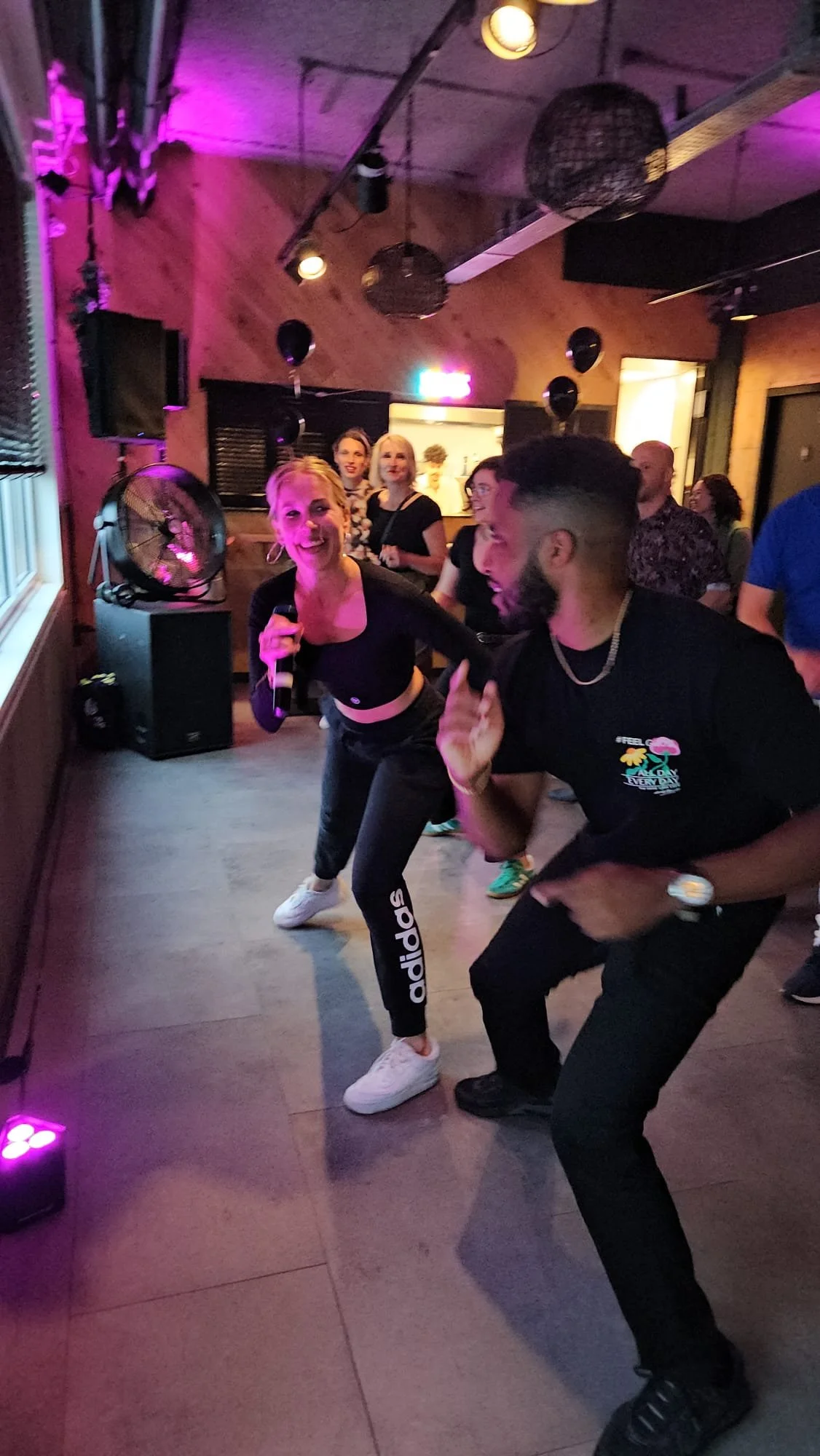 People dancing and having fun at a party or nightclub with colorful lighting.