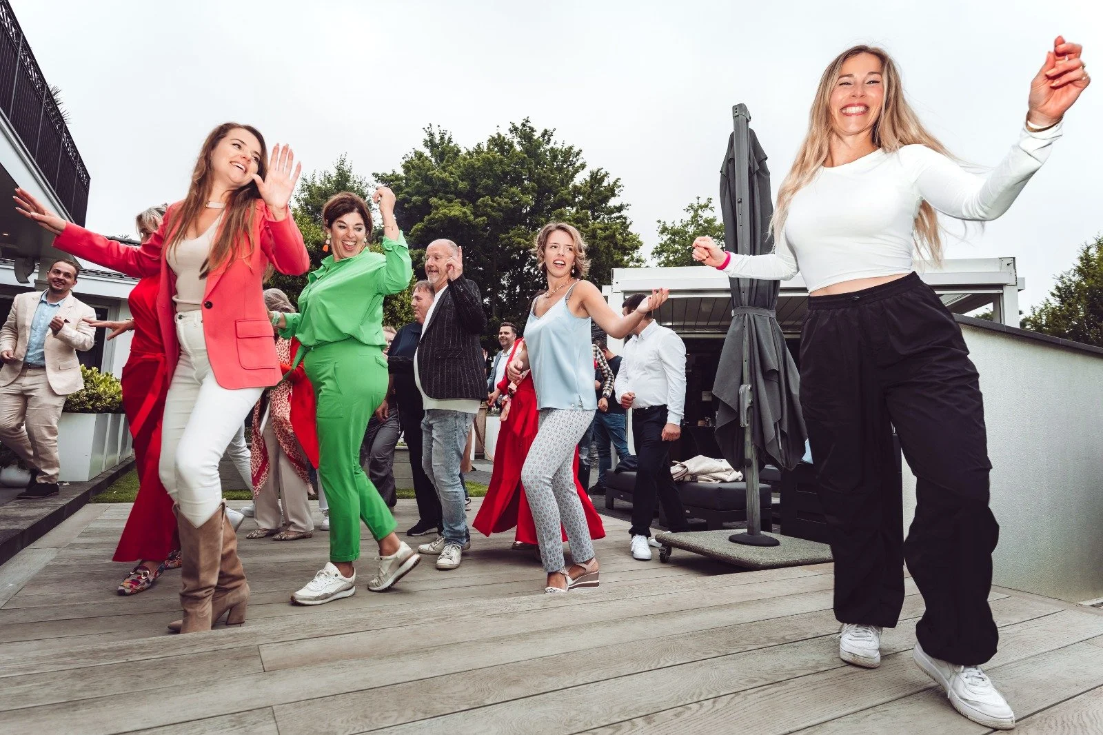 Group of friends dancing and having fun on a deck during an outdoor gathering.