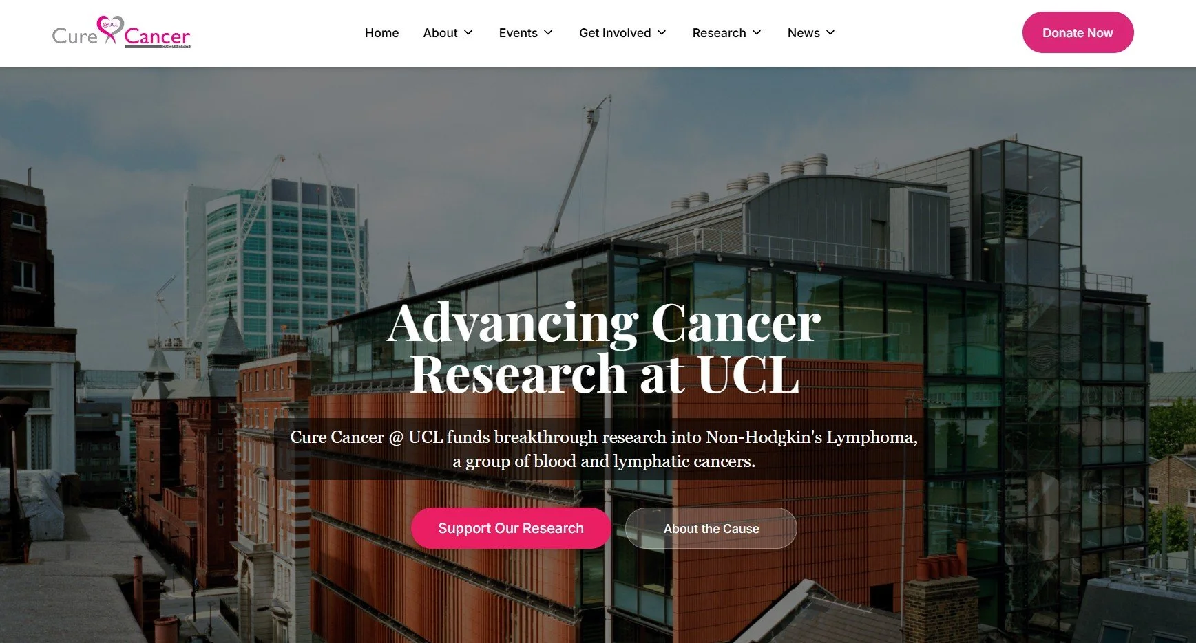 A modern urban building with glass facades and red brick elements, with a city skyline and cloudy sky in the background.